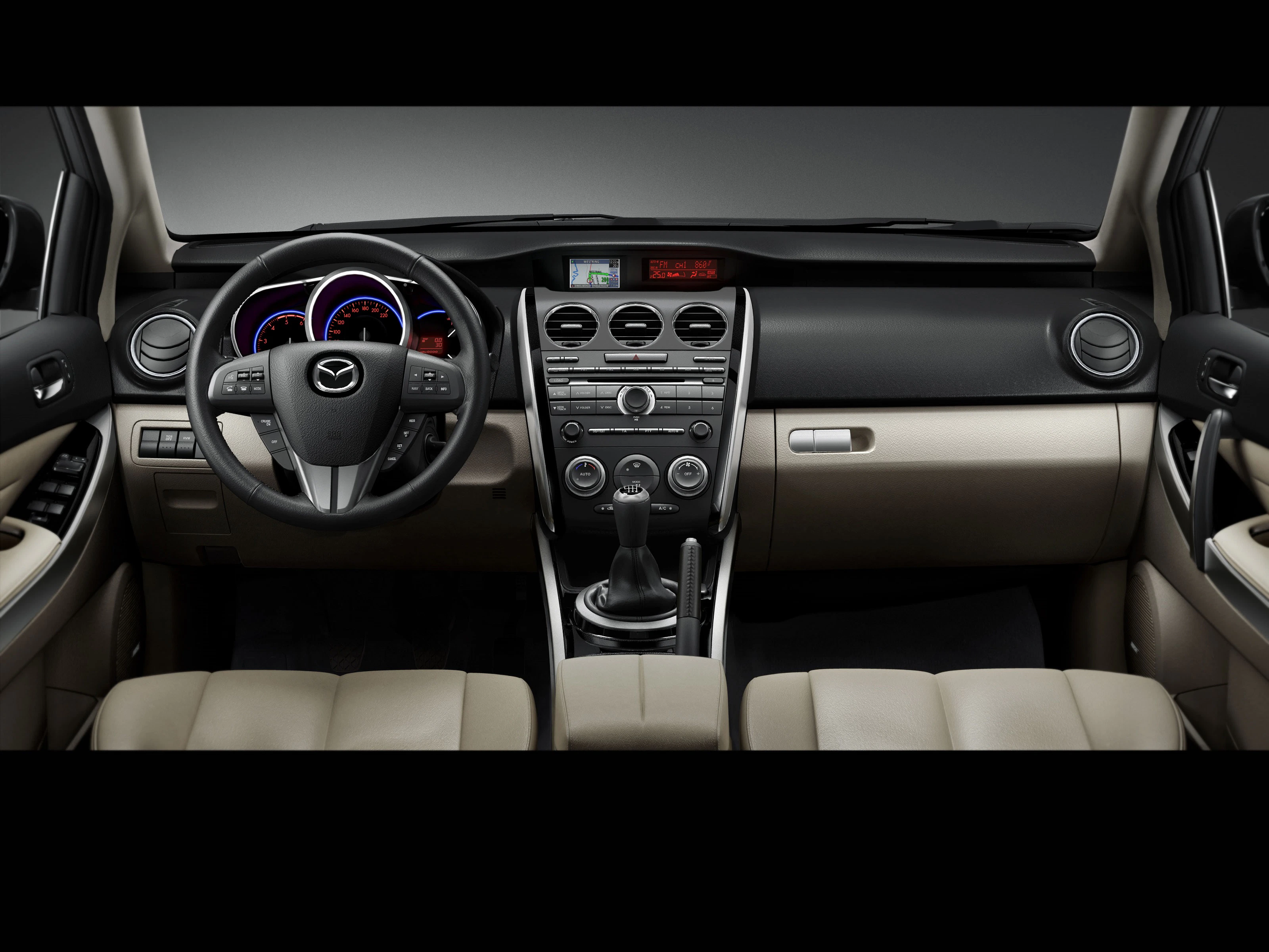 Innenraum eines Mazda-Autos mit beigem Leder, Armaturenbrett mit Rundinstrumenten, Mittelkonsole mit Schaltknüppel und Klimasteuerung.