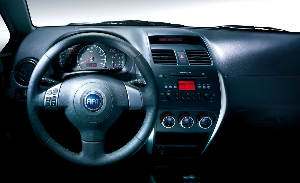 Innenansicht eines Fiat-Autos mit Lenkrad, Tachometer und Mittelkonsole mit Radio und Lüftungsregelungen.