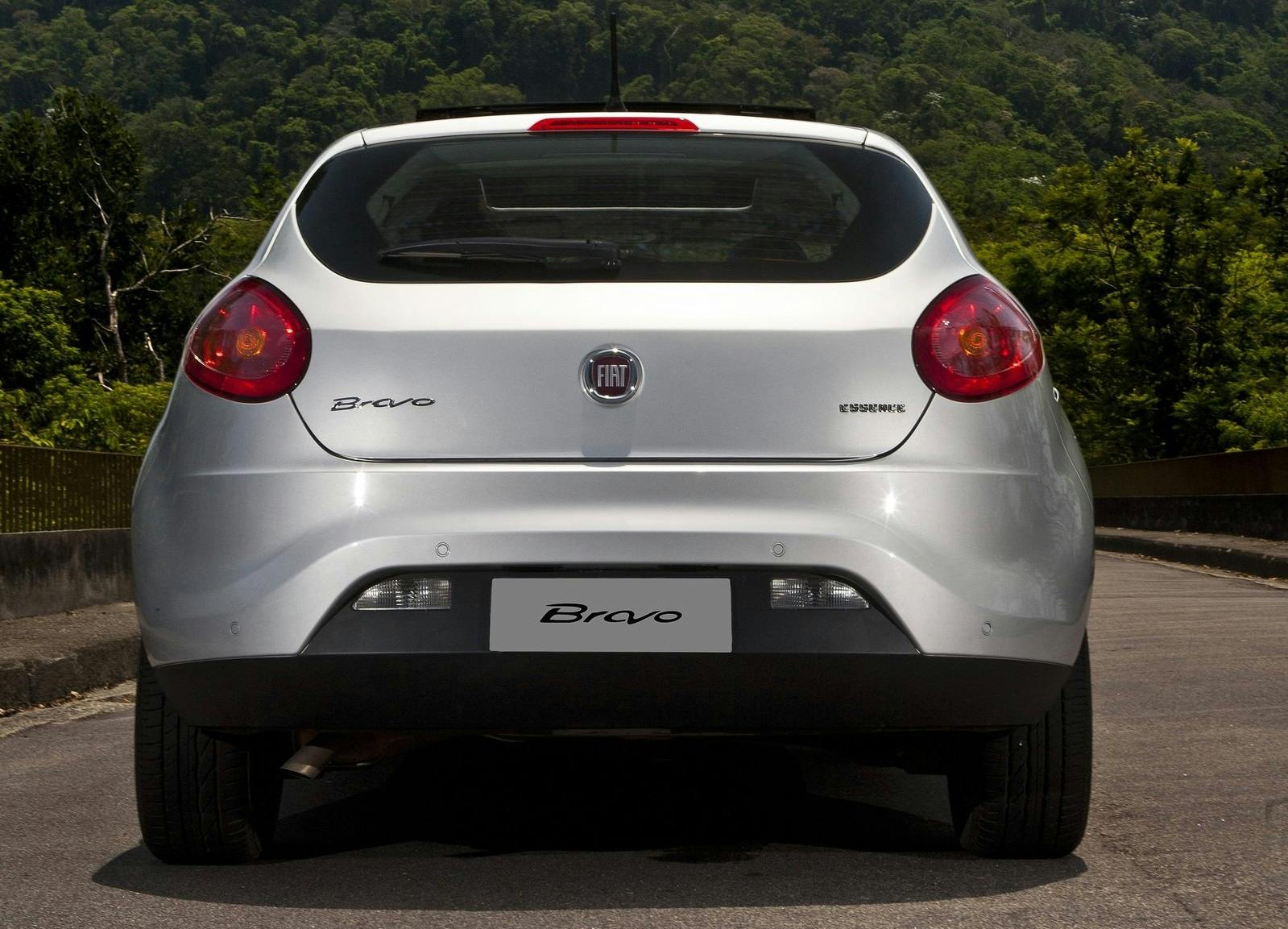 Rückansicht eines silbernen Fiat Bravo auf einer Straße, umgeben von üppiger, grüner Vegetation im Hintergrund.
