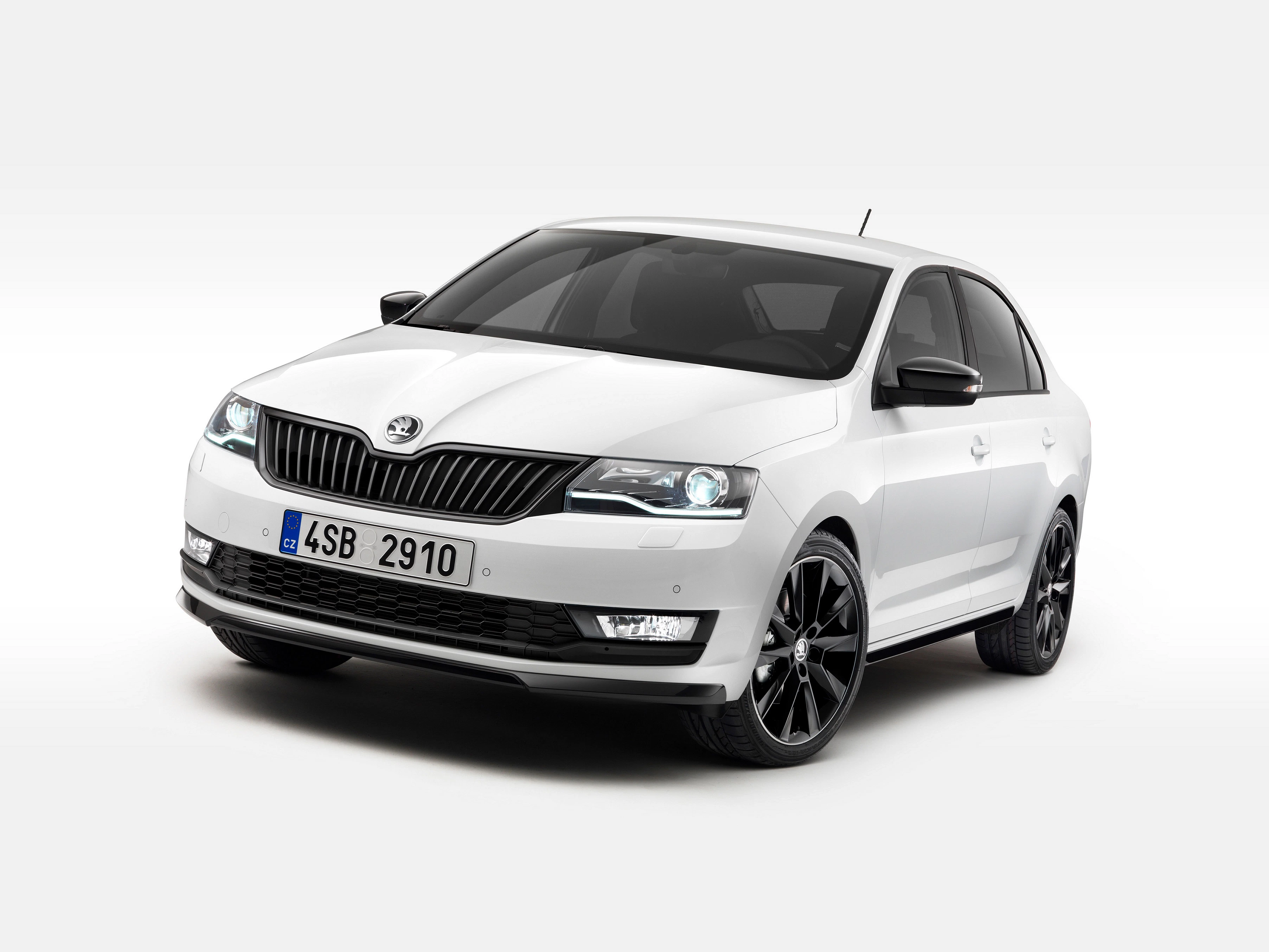 Weißer Škoda Rapid von vorne, stehend auf hellem Hintergrund. Elegantes Design mit schwarzen Felgen und markantem Kühlergrill.