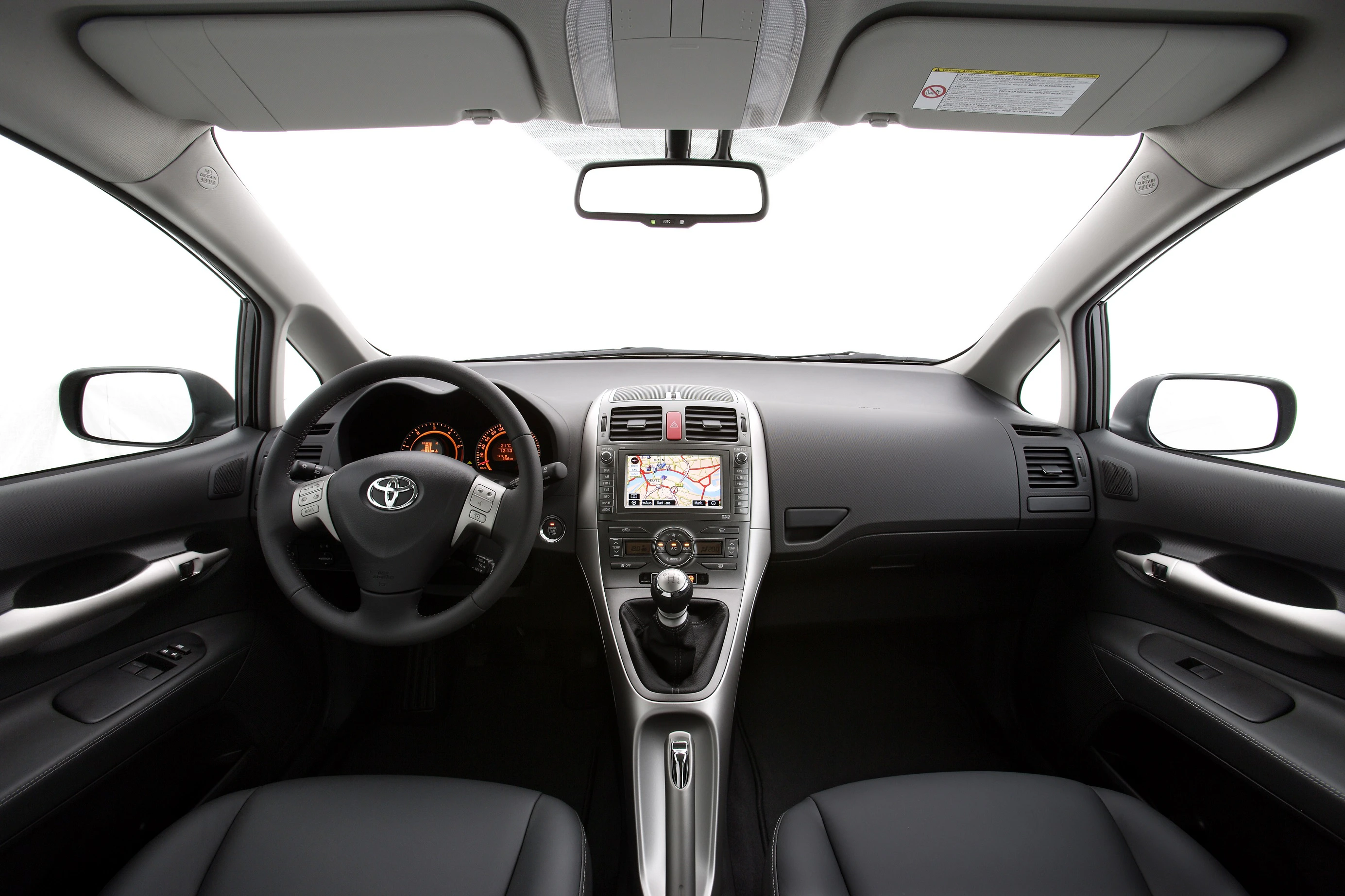 Innenraum eines Autos mit Lenkrad, Armaturenbrett, Navigationssystem und Gangschaltung. Moderne Ausstattung in gedeckten Farben.