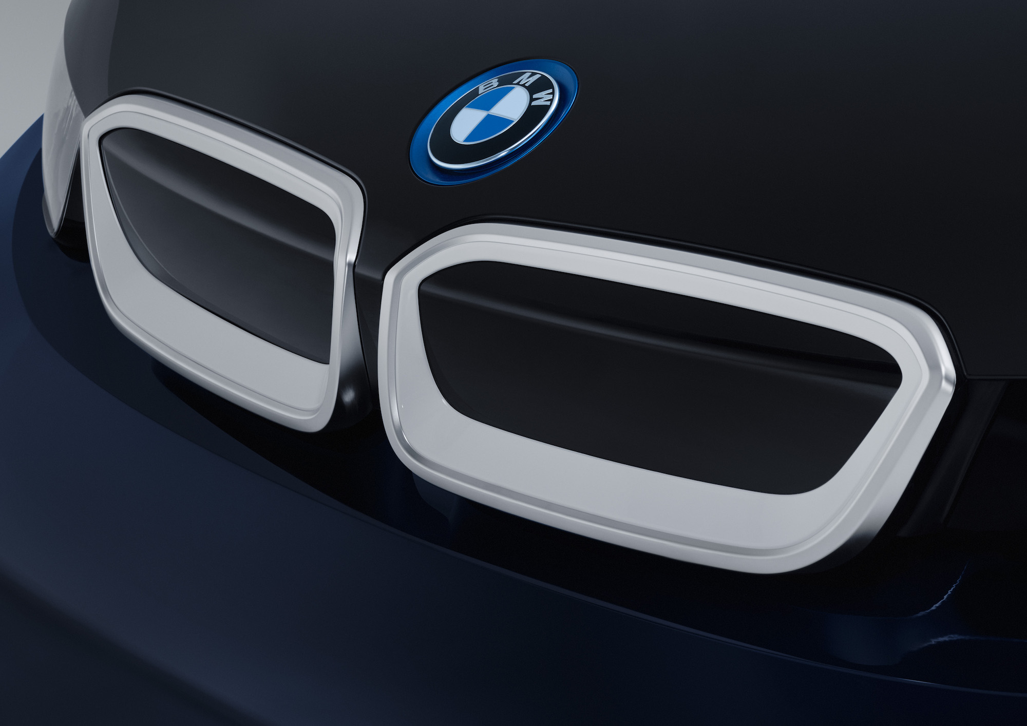 Nahaufnahme des Kühlergrills eines schwarzen BMW-Fahrzeugs mit blau-weißem Logo und silbernen Umrandungen.
