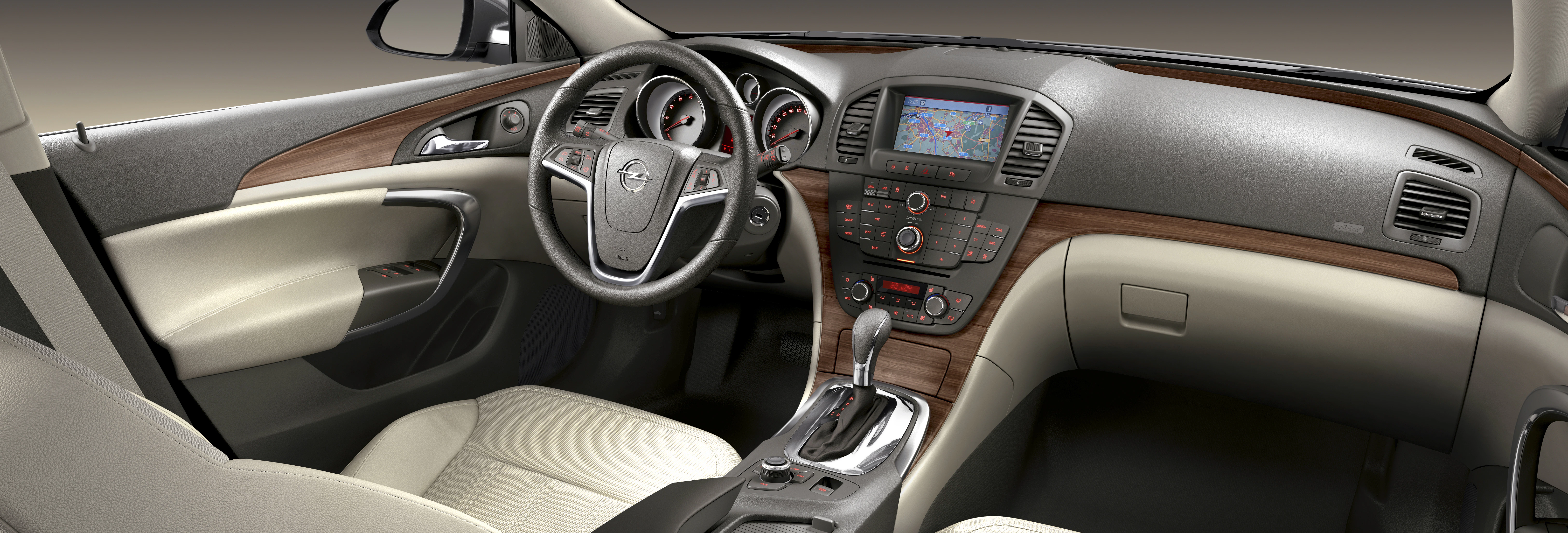 Innenraum eines Autos mit beigem Leder, Holzverkleidungen, Lenkrad, Mittelkonsole mit Schaltknauf und integriertem Display.