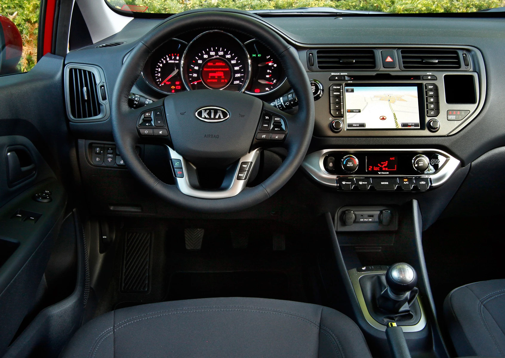 Innenansicht eines Kia-Autos mit modernem Armaturenbrett, Touchscreen-Navigationssystem, Multifunktionslenkrad und manueller Schaltung.