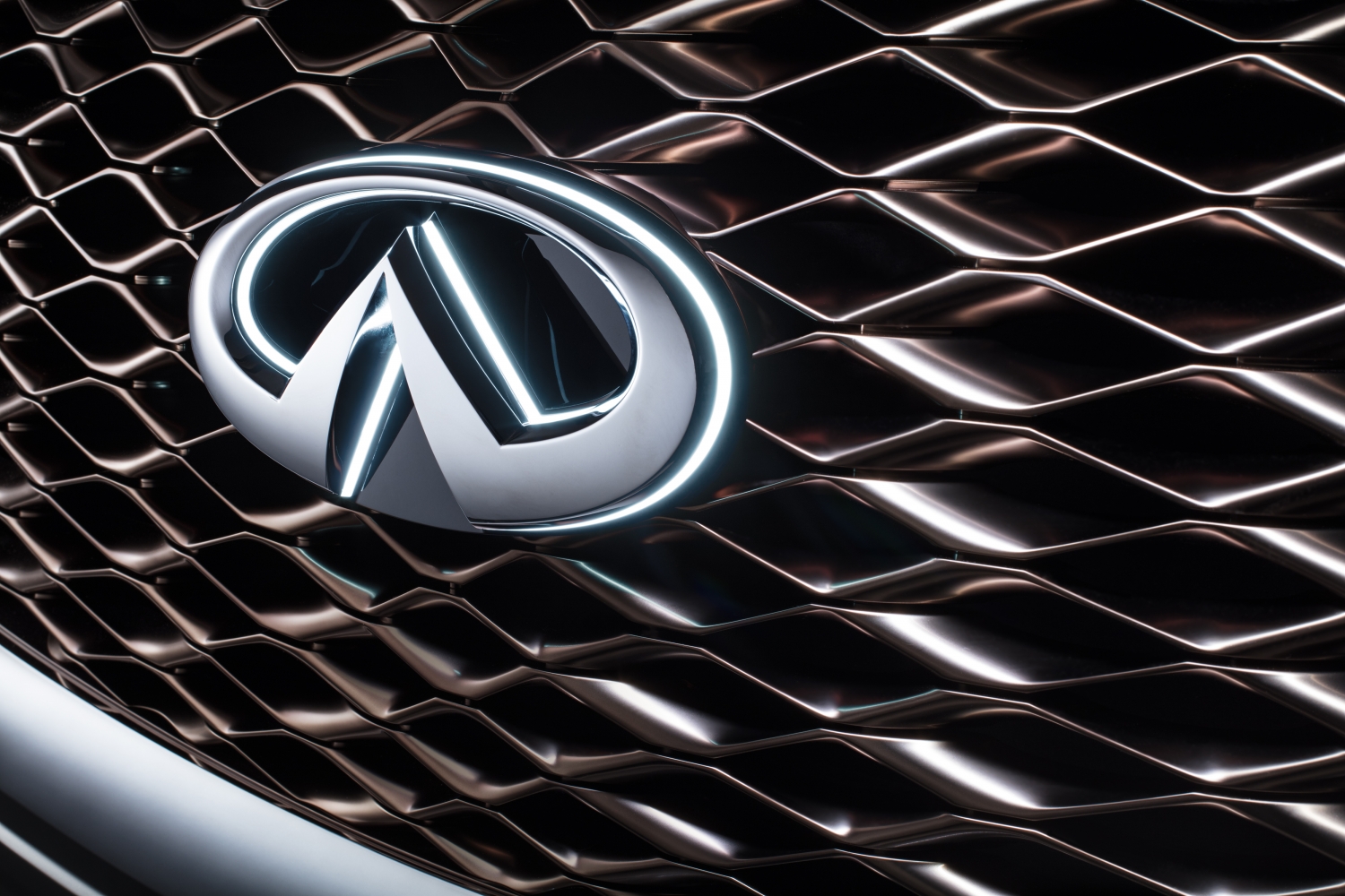 Nahaufnahme eines Kühlergrills mit dem silbernen Emblem einer Automarke. Das Gittermuster hat einen glänzenden, modernen Look.