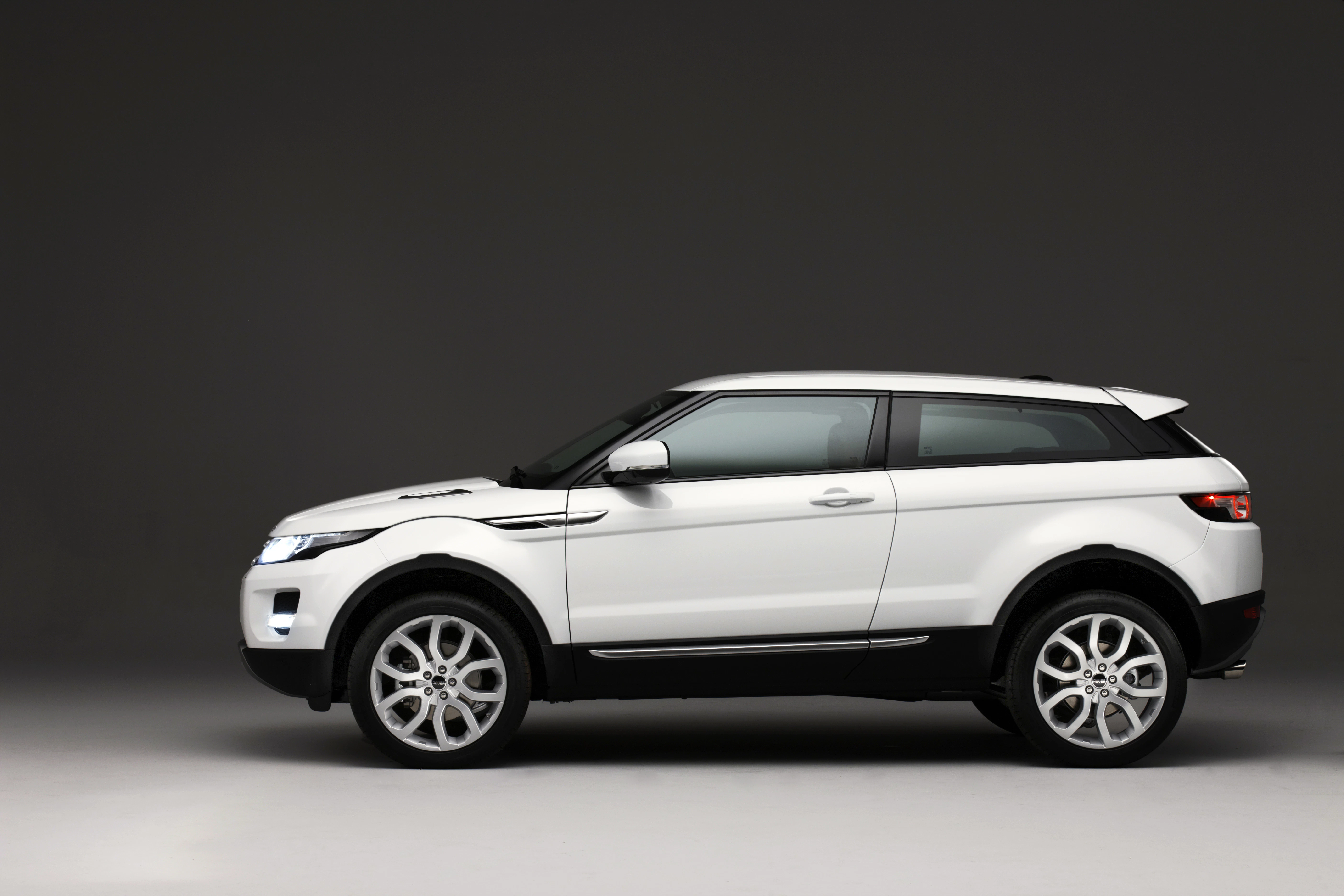 Weißes SUV in Seitenansicht vor grauem Hintergrund, modernes Design mit schwarzen Akzenten und auffälligen Felgen.