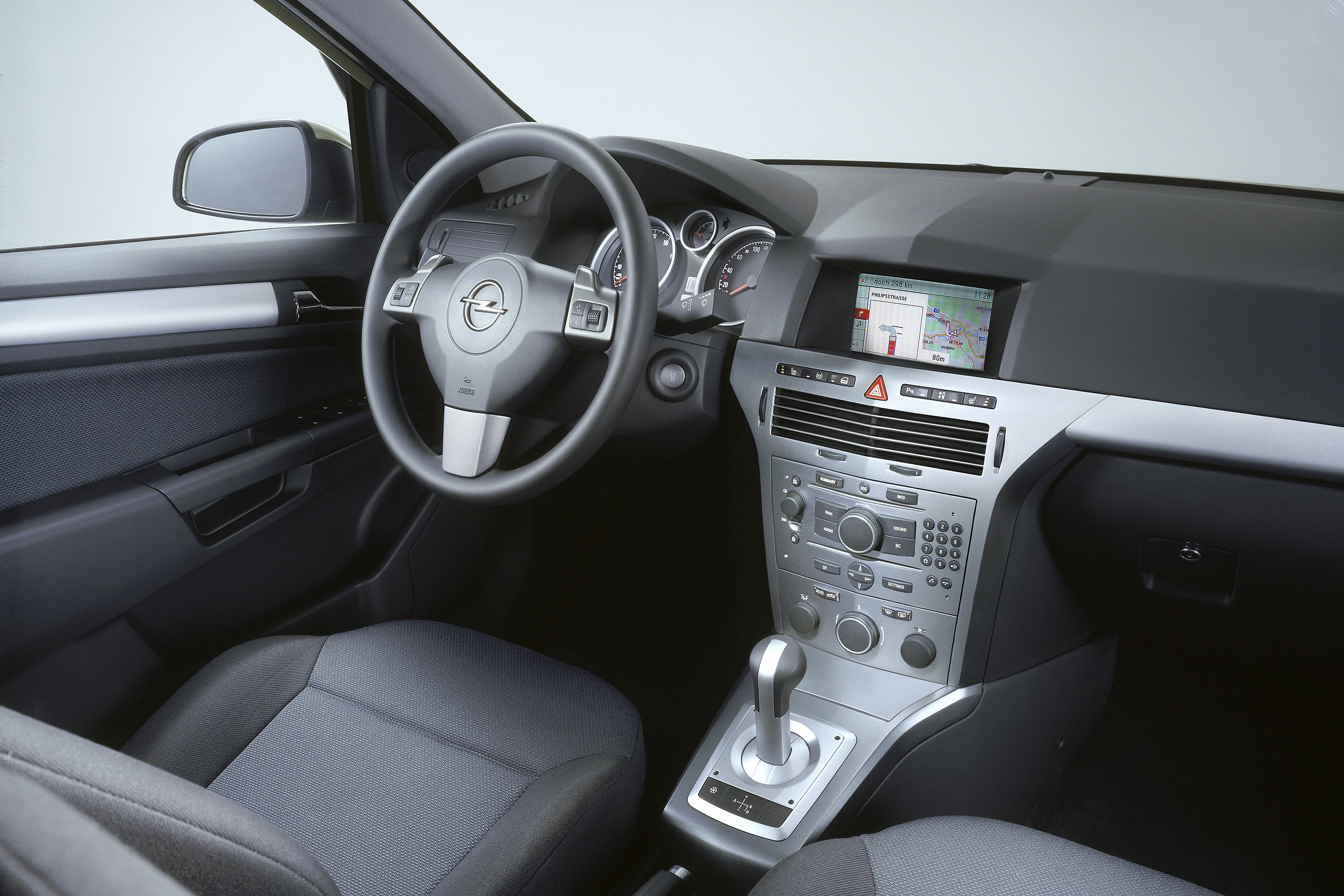 Innenraum eines Autos mit grauem Interieur, zentralem Touchscreen-Display und Automatikgetriebe. Sicht auf Lenkrad und Armaturenbrett.