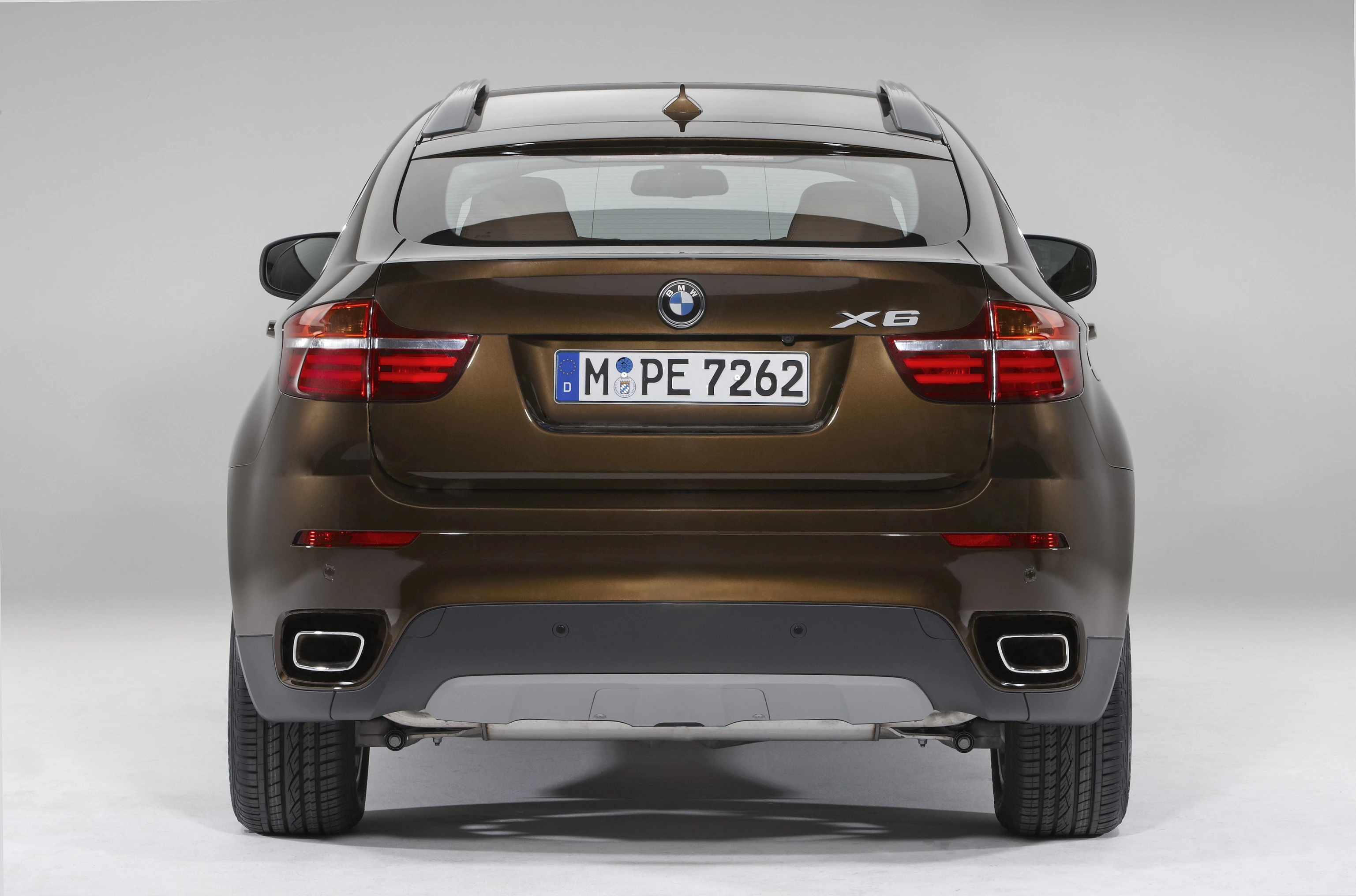 Brauner BMW X6 von hinten, auf grauem Hintergrund. Sichtbar sind die Rücklichter, der Kofferraum und das Nummernschild.