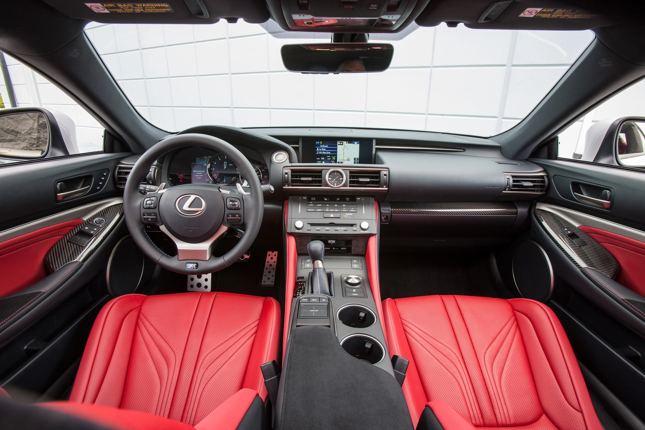 Innenraum eines Autos mit roten Ledersitzen, modernem Armaturenbrett und zentralem Display. Markenlogo auf dem Lenkrad. Moderne Ausstattung.