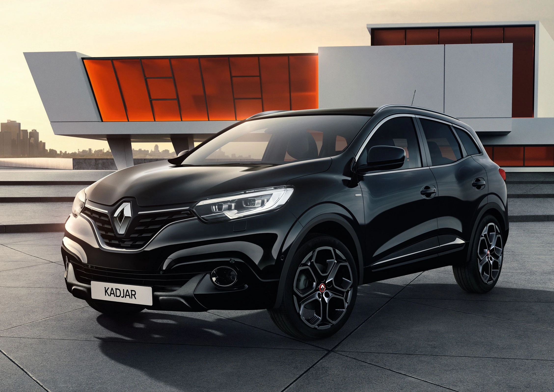 Schwarzer Renault Kadjar SUV steht vor moderner Architektur im Sonnenuntergang.