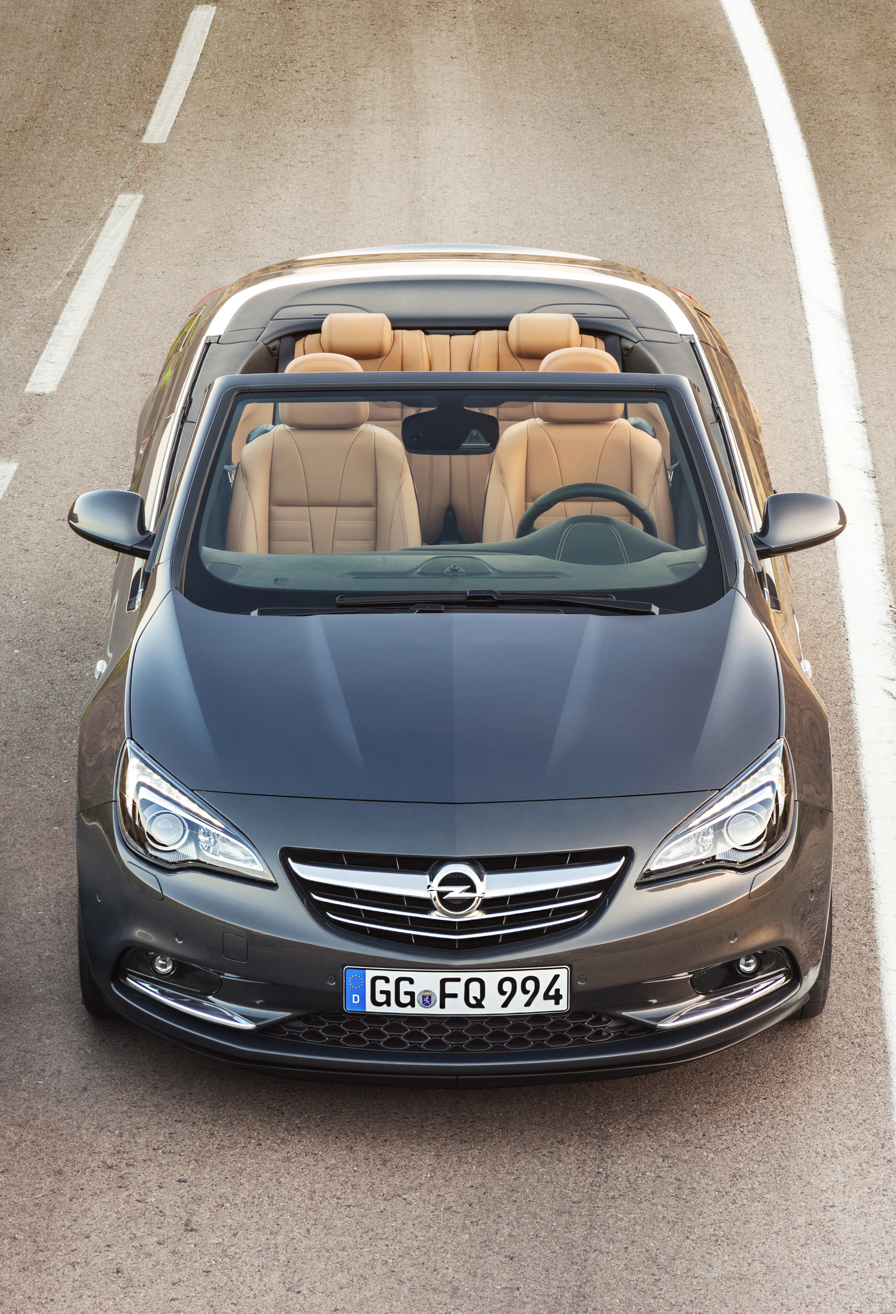 Graues Cabriolet von oben auf einer Straße, mit geöffnetem Verdeck und beigen Ledersitzen. Europäisches Nummernschild sichtbar.