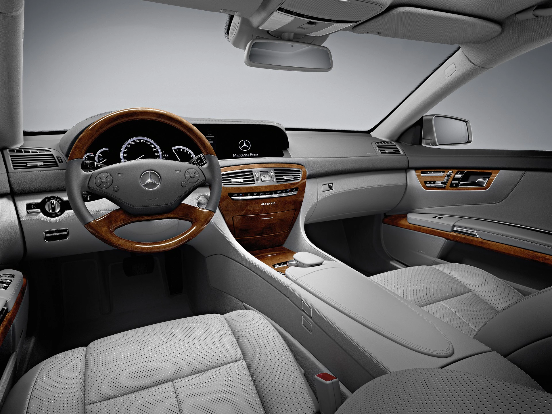 Innenraum eines luxuriösen Autos mit Holzdekor, elegantem Armaturenbrett und Ledersitzen. Mercedes-Benz-Logo auf dem Lenkrad sichtbar.