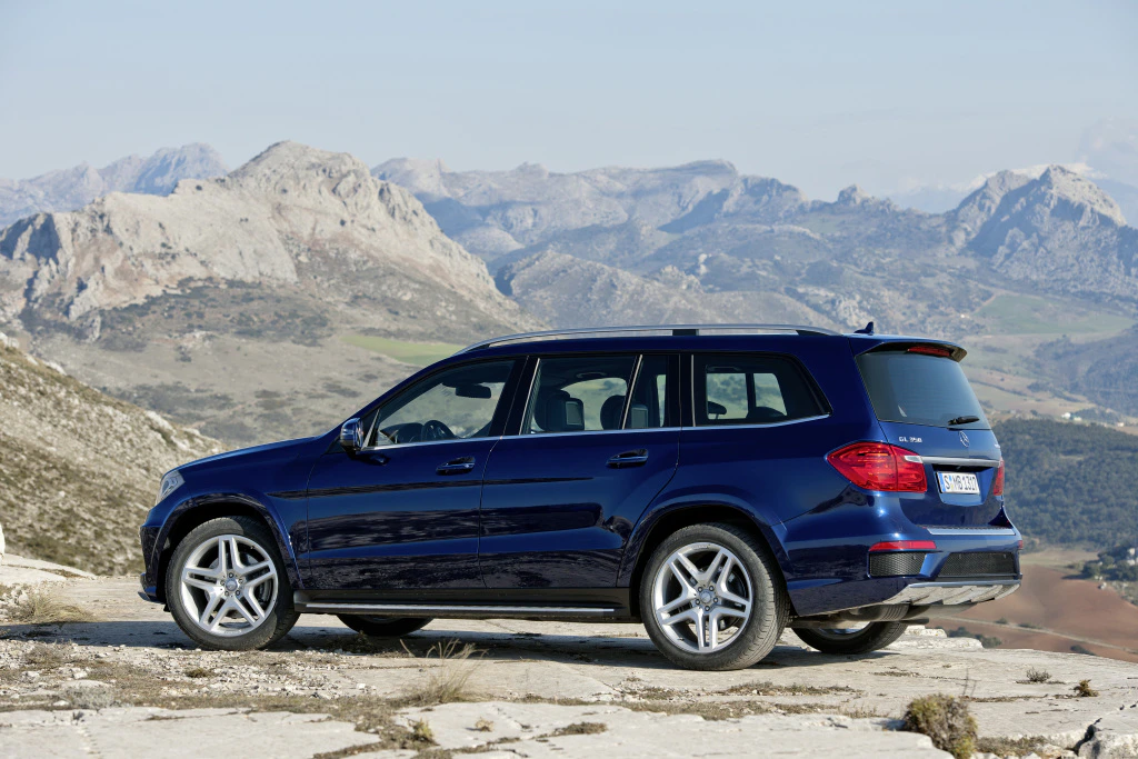 Dunkelblauer SUV auf einem Bergplateau mit felsiger Landschaft im Hintergrund unter klarem Himmel.