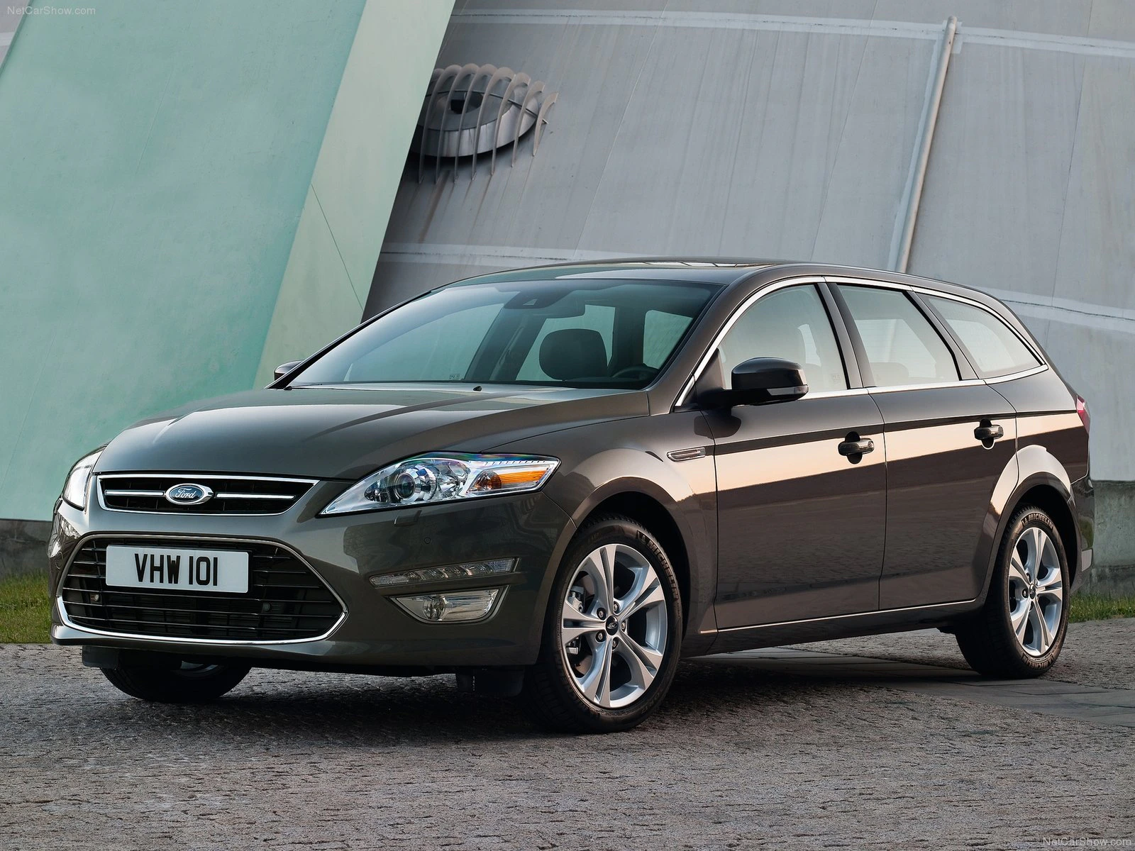 Brauner Ford Mondeo Kombi steht auf einer gepflasterten Straße vor einer modernen Gebäude-Kulisse.