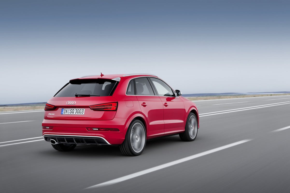 Roter Audi Q3 fährt auf einer leeren Autobahn bei klarem Himmel. Rückansicht des Autos mit dynamischem Fahrgefühl.