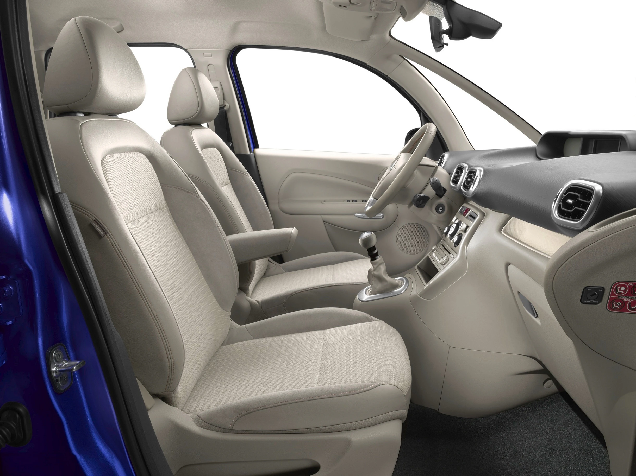Innenraum eines Autos mit beiger Polsterung, Vordersitze, Armaturenbrett mit Schalthebel und Lenkrad sichtbar. Modernes, schlichtes Design.
