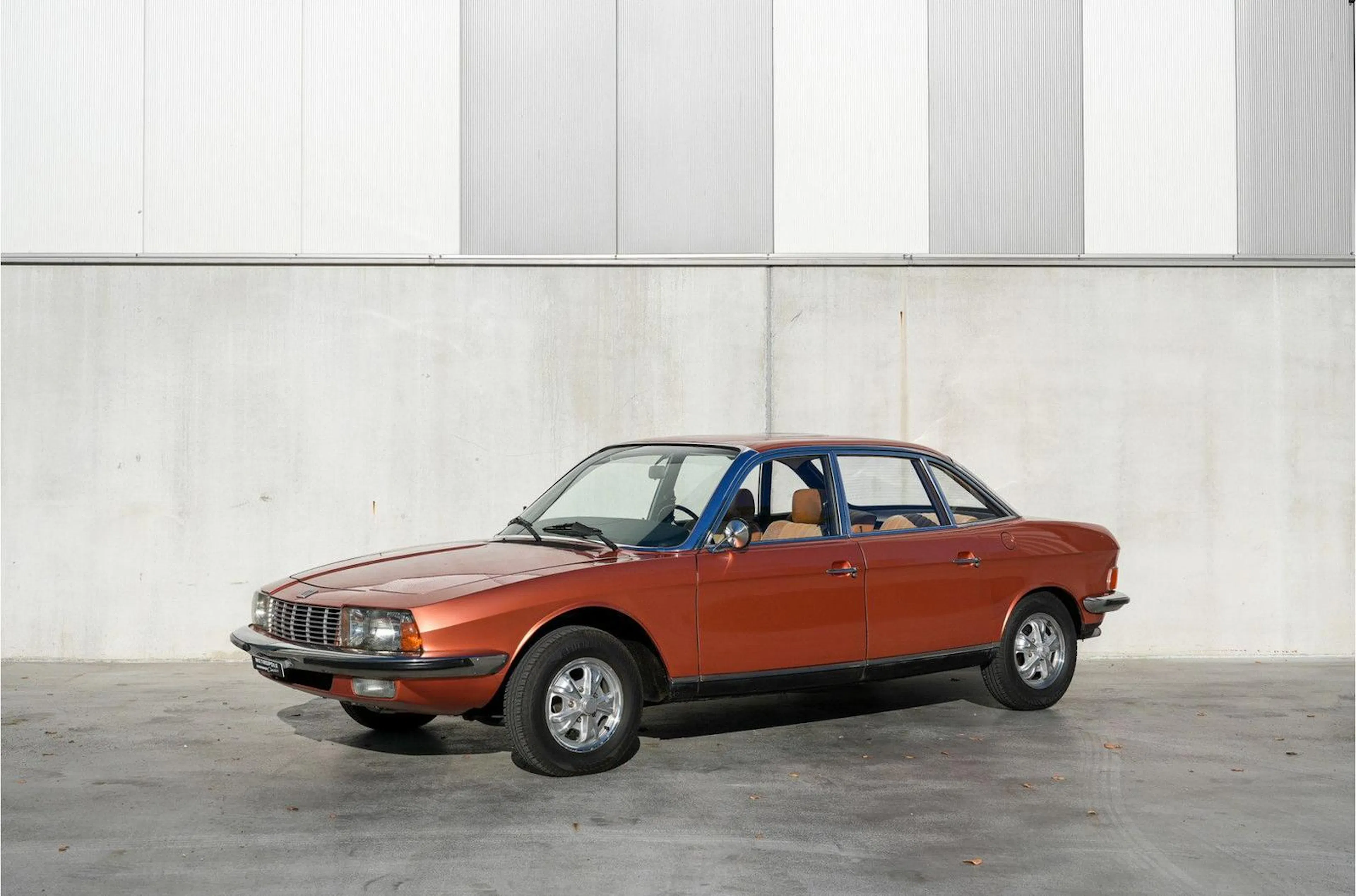 Rot-brauner NSU Ro80 steht vor einer Betonwand