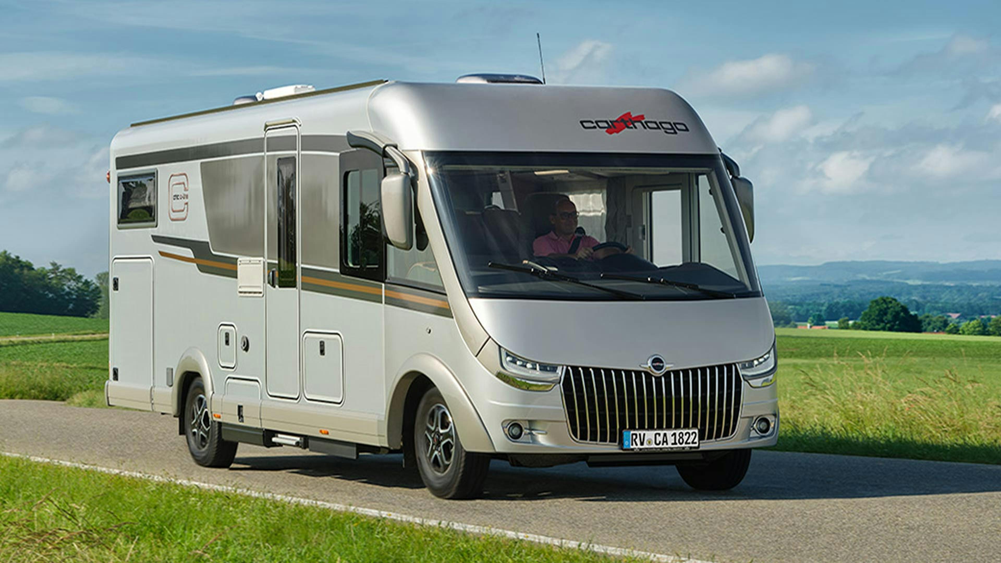 Ein Carthago Chic C-Line Wohnmobil fährt eine Landstraße entlang.