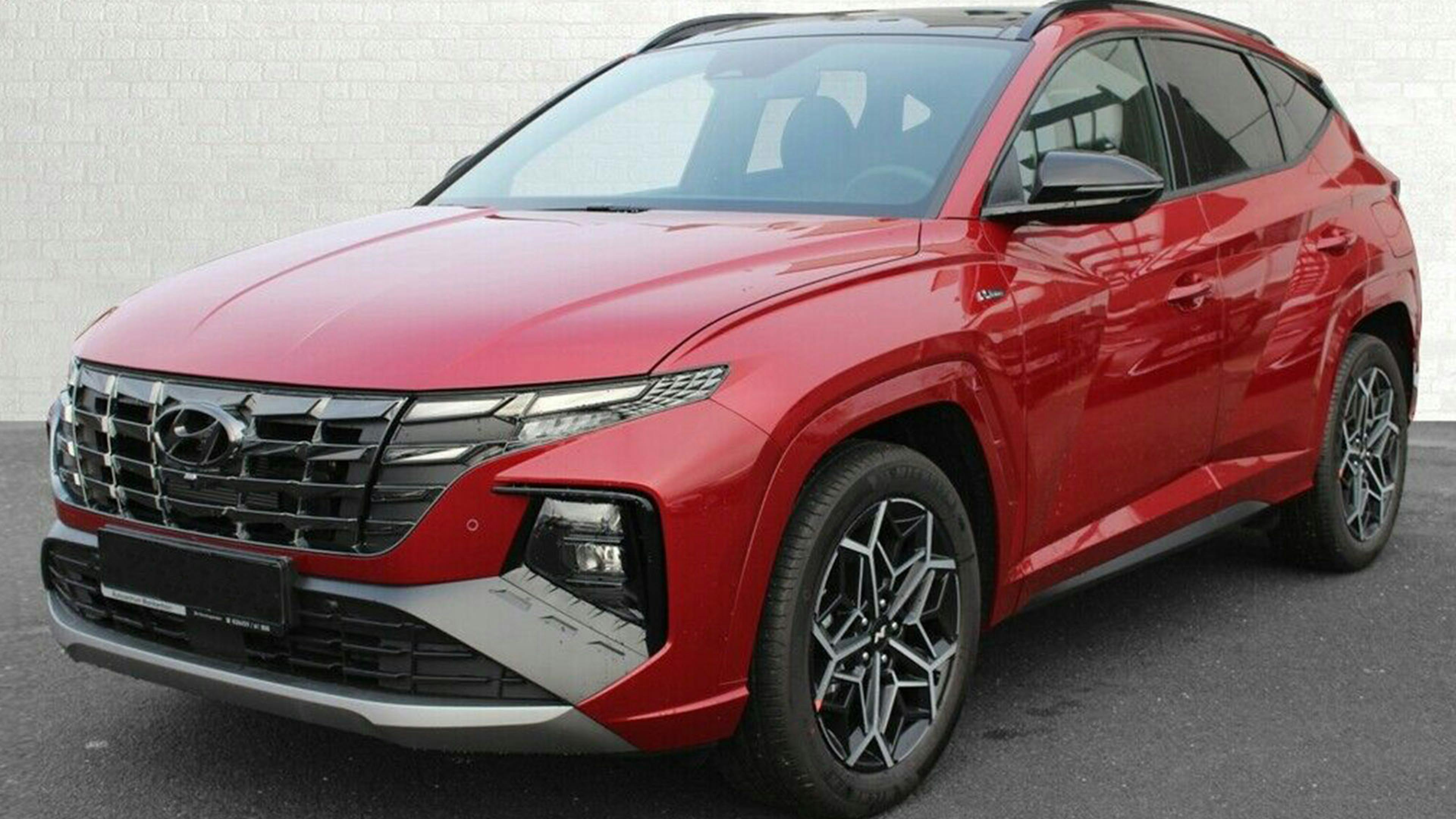 Ein roter Hyundai Tucson steht vor einer weißen Wand
