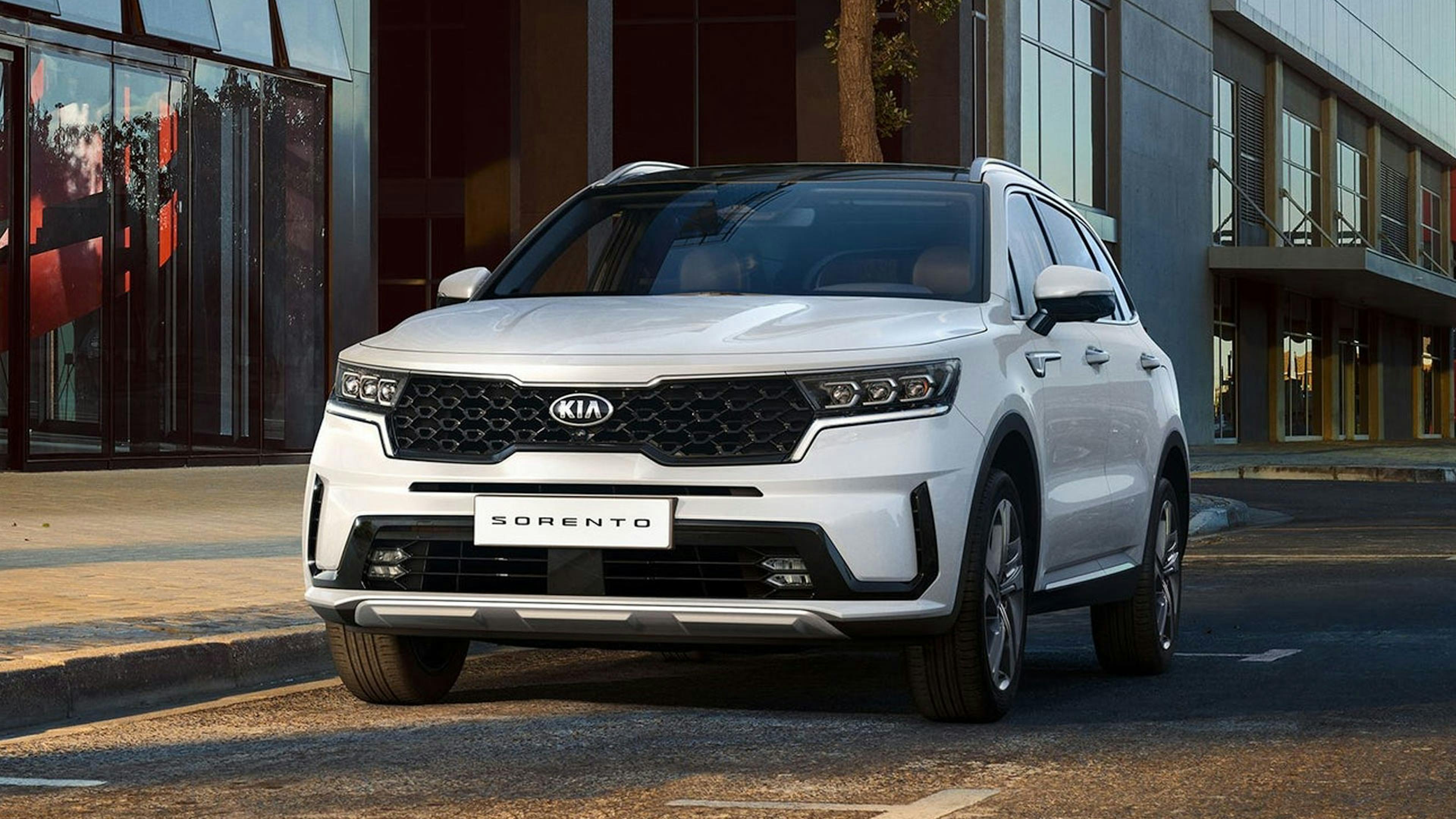 Ein weißer Kia Sorento Hybrid steht vor einem Gebäude.