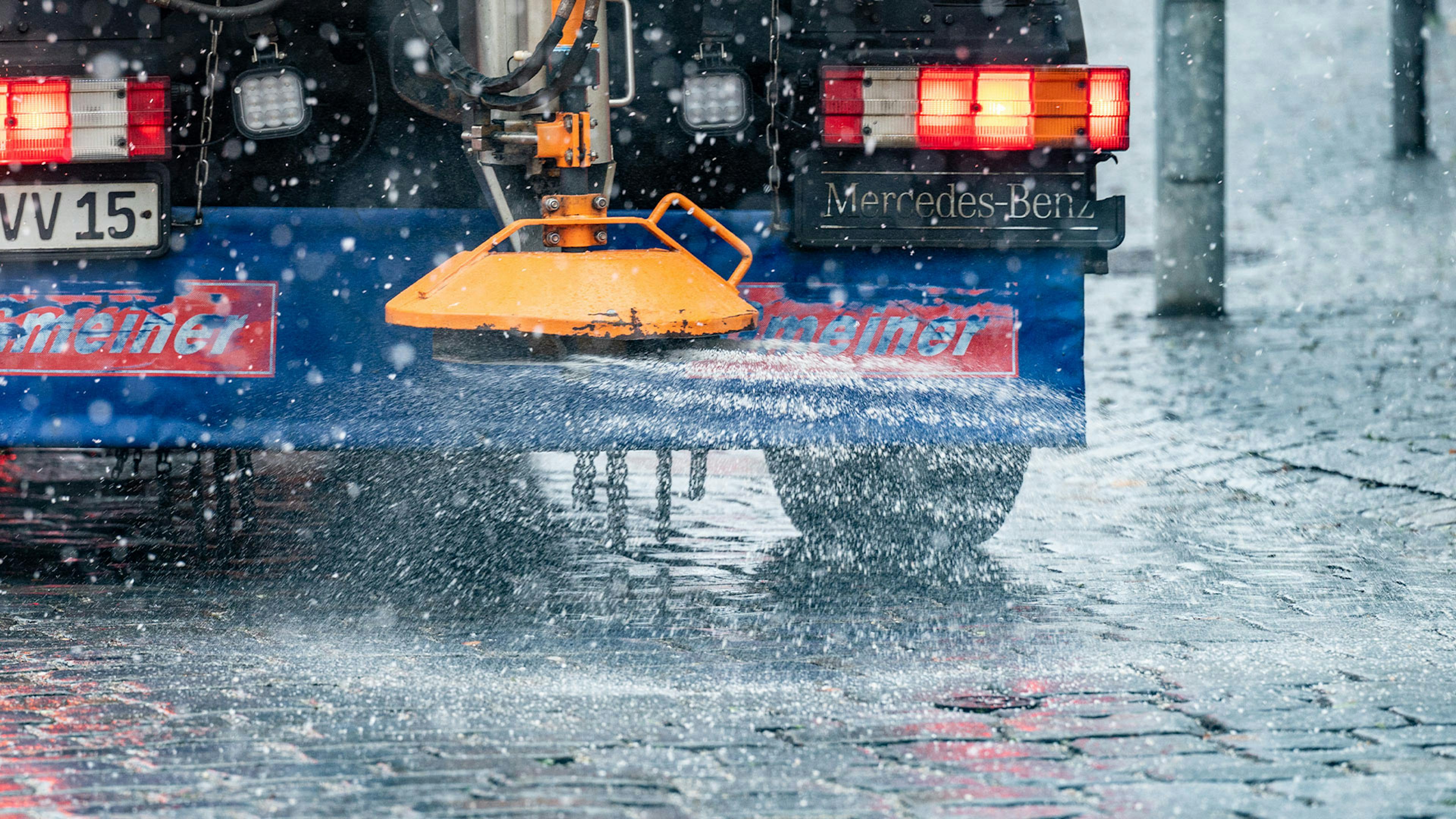 Ein Fahrzeug des Winterdienstes streut Salz auf eine Straße.