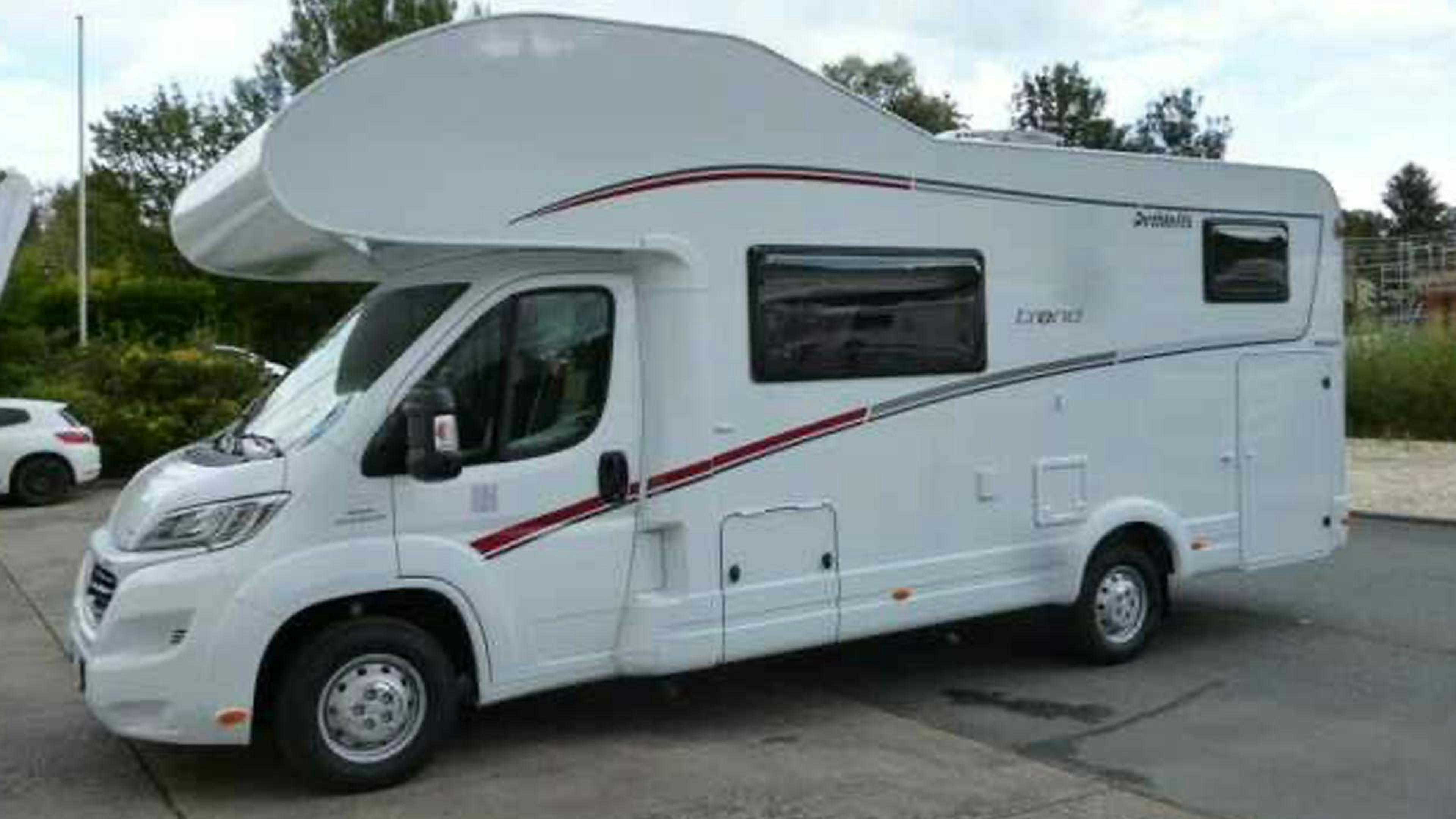 Ein Dethleffs Trend Wohnmobil mit Alkoven steht auf einem Parkplatz.