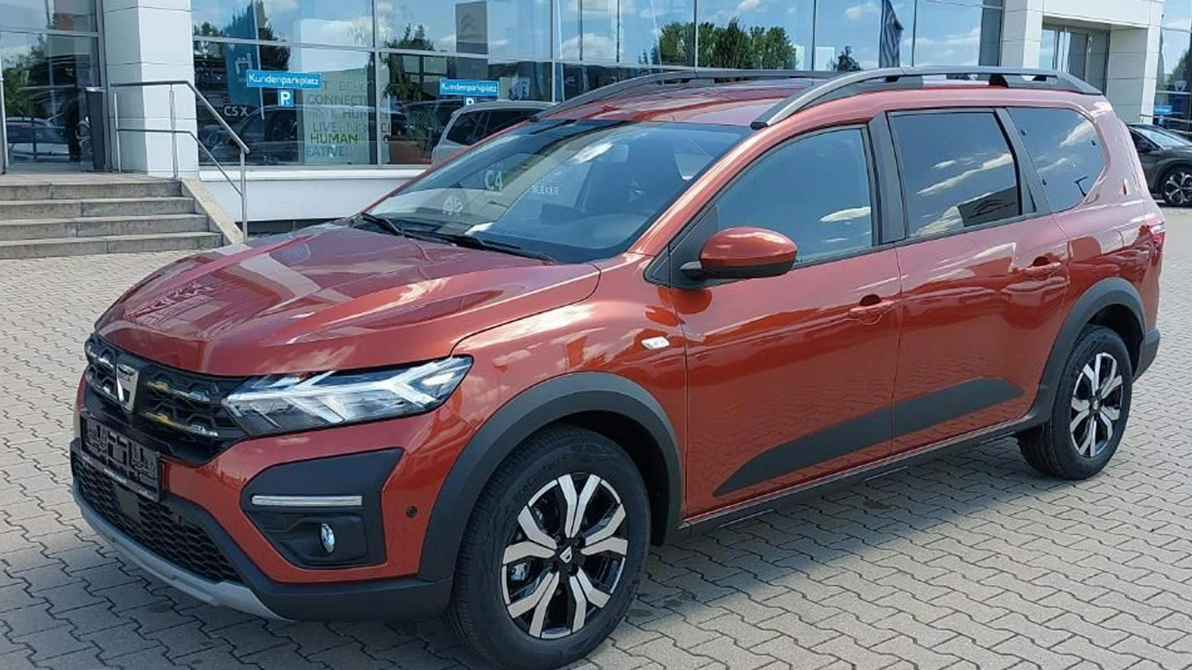 Ein roter Dacia Jogger steht vor einem Autohaus.