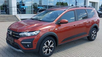 Ein roter Dacia Jogger steht vor einem Autohaus.