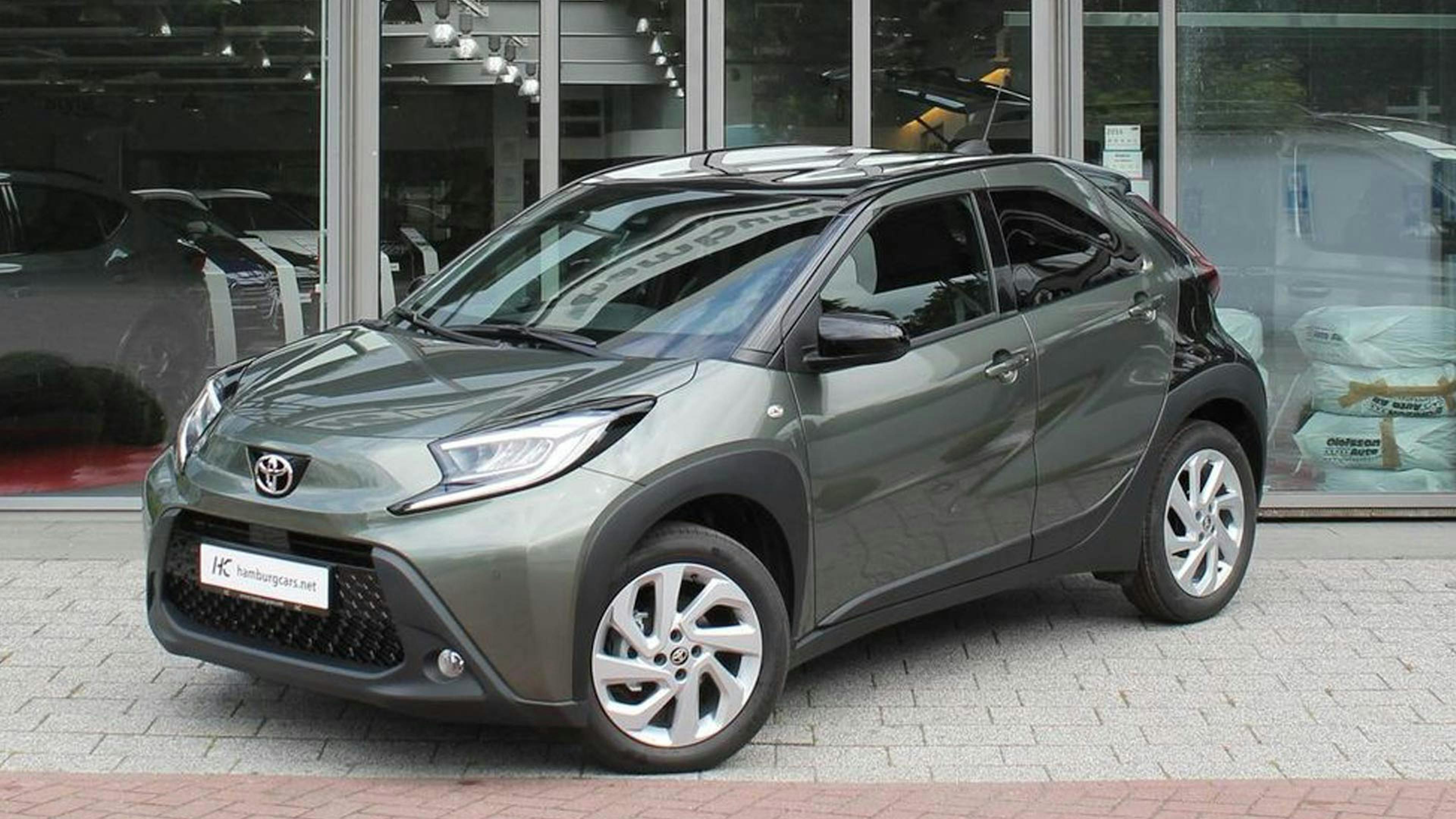 Ein grauer Toyota Aygo steht vor einem Autohaus.