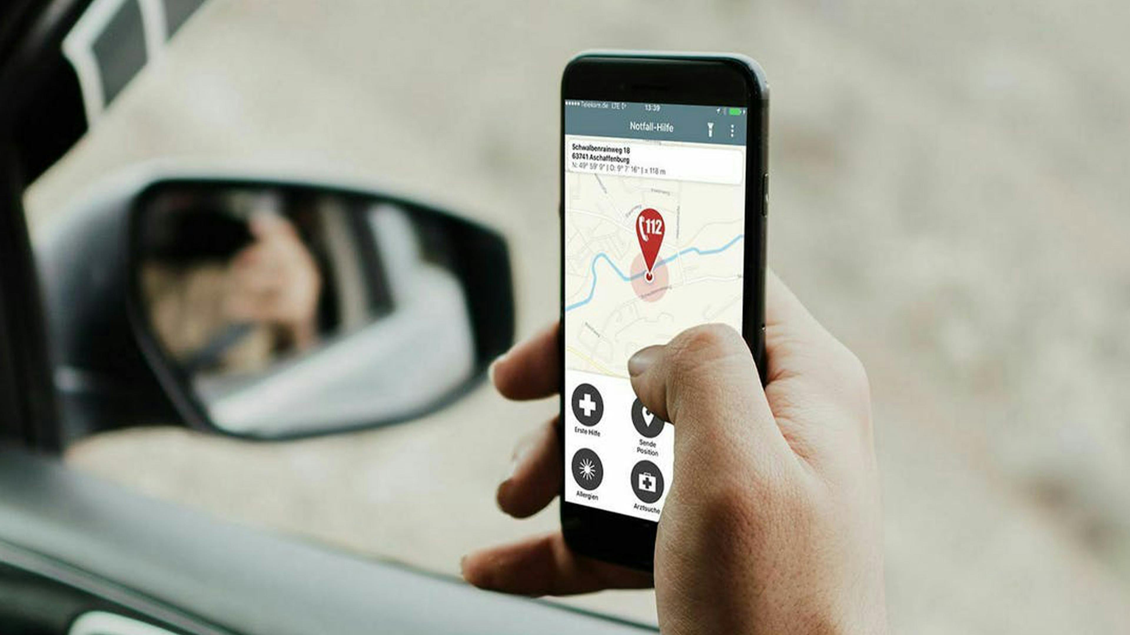 Detailaufnahme einer Hand mit einem Smartphone, auf dem eine Notfall-App geöffnet ist