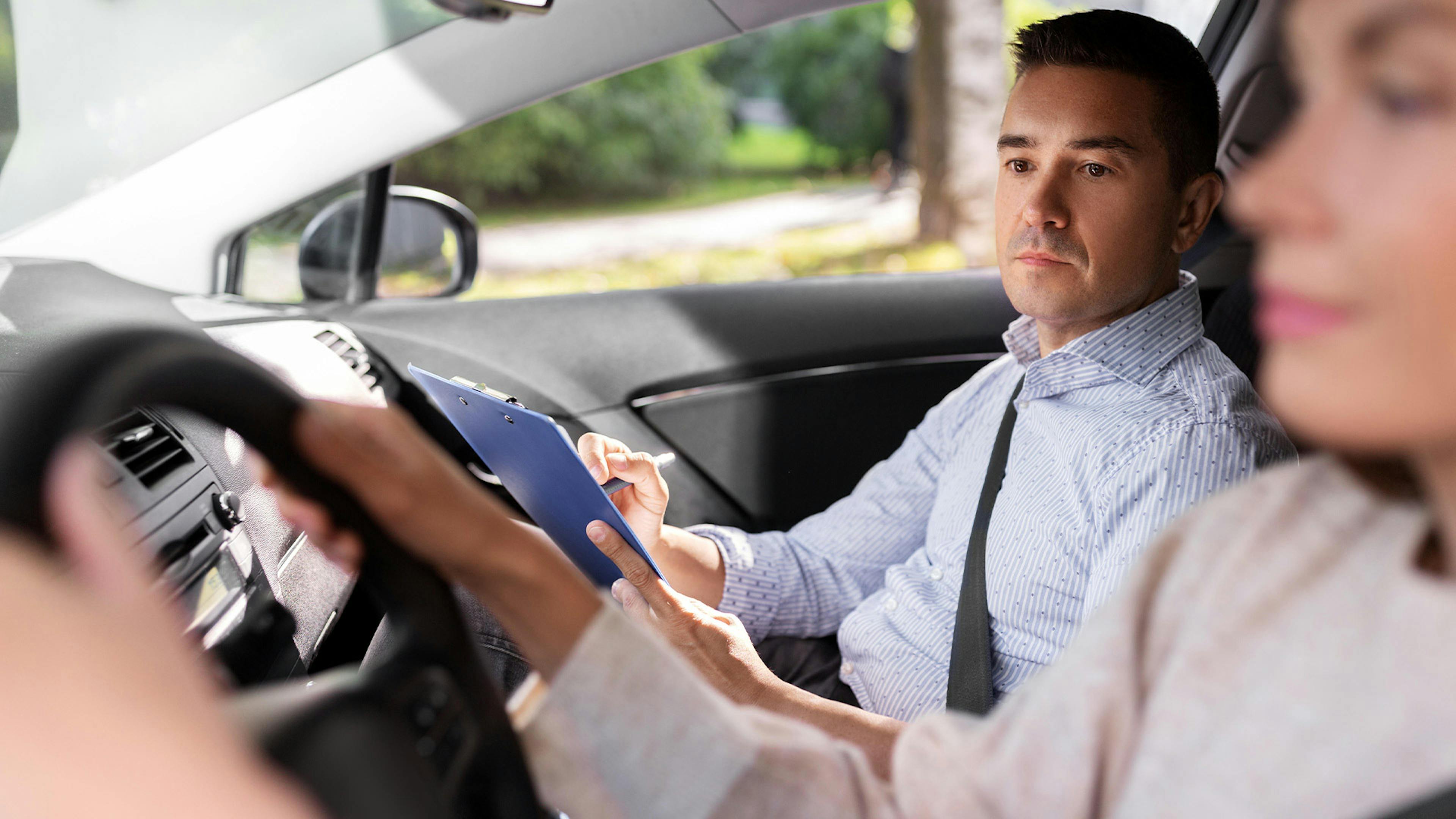 Eine junge Frau und ein Fahrlehrer sitzen in einem Pkw bei einer Führerscheinprüfung