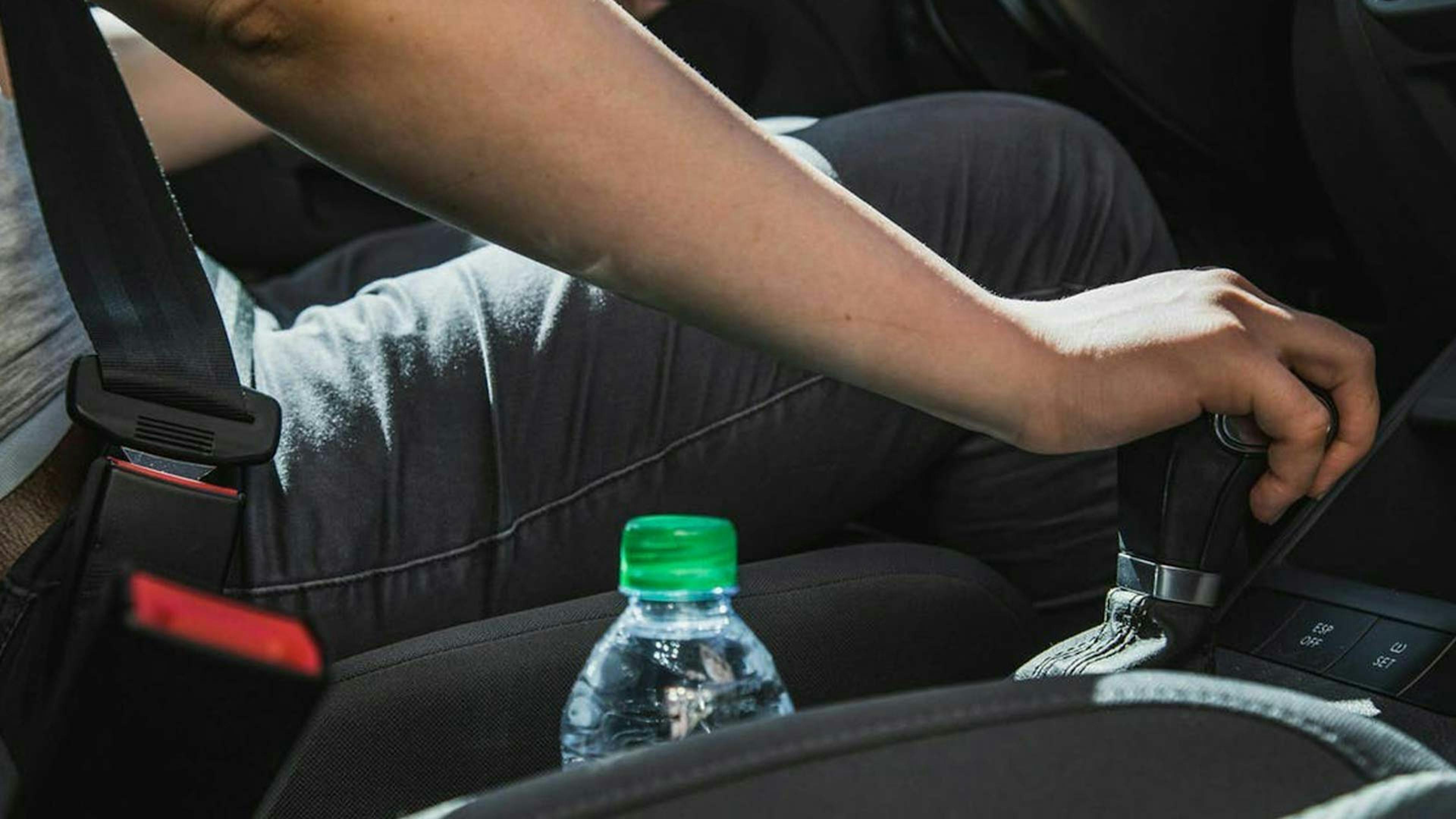 Eine Person sitzt auf dem Fahrersitz eines Pkw und betätigt die Schaltung.