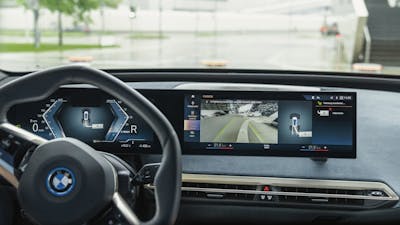 Blick in das Cockpit eines BMW iX mit eingeschaltetem Parkassistenzsystem