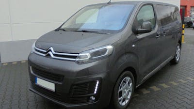 Ein grauer Citroën e-Spacetourer steht vor einem weiß-grauen Gebäude.
