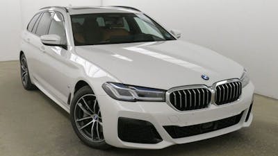 Ein weißer BMW 5er Touring steht vor einer weißen Wand.