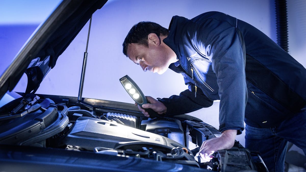 Ein Automechaniker untersucht den Motorraum eines Pkw.