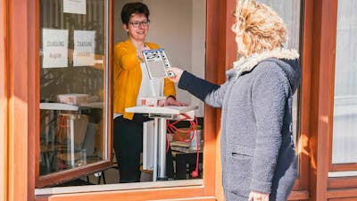 Eine Frau überreicht einer Kundin ein Wechselkennzeichen in einer Kfz-Zulassungsstelle