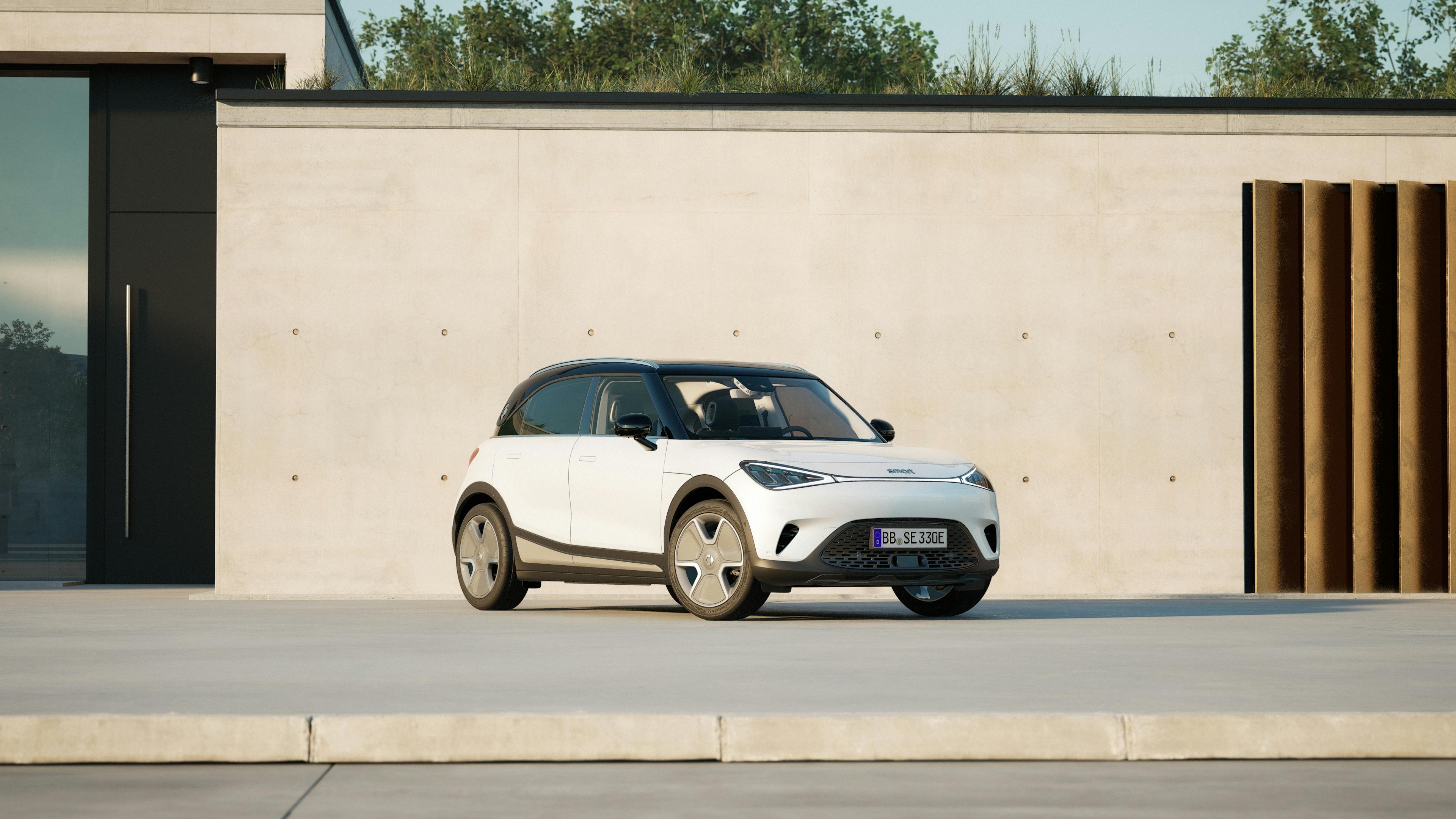 A white Smart #1 is parked in front of the concrete wall of a house.