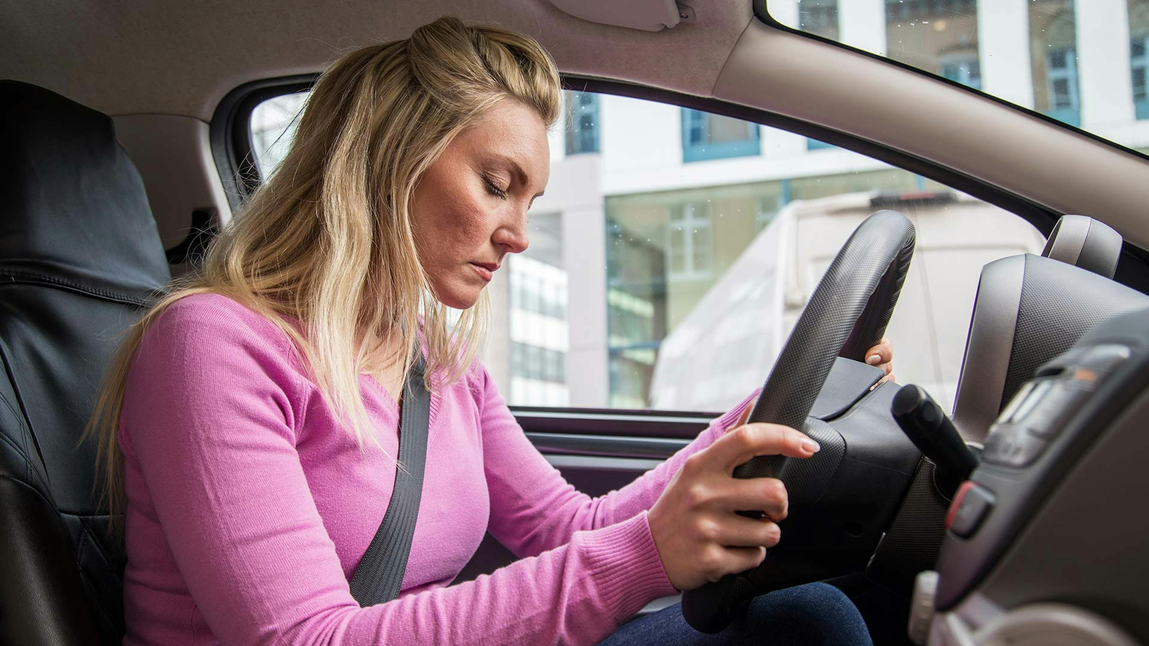 Eine Frau kämpft mit der Müdigkeit beim Autofahren und fällt in einen Sekundenschlaf