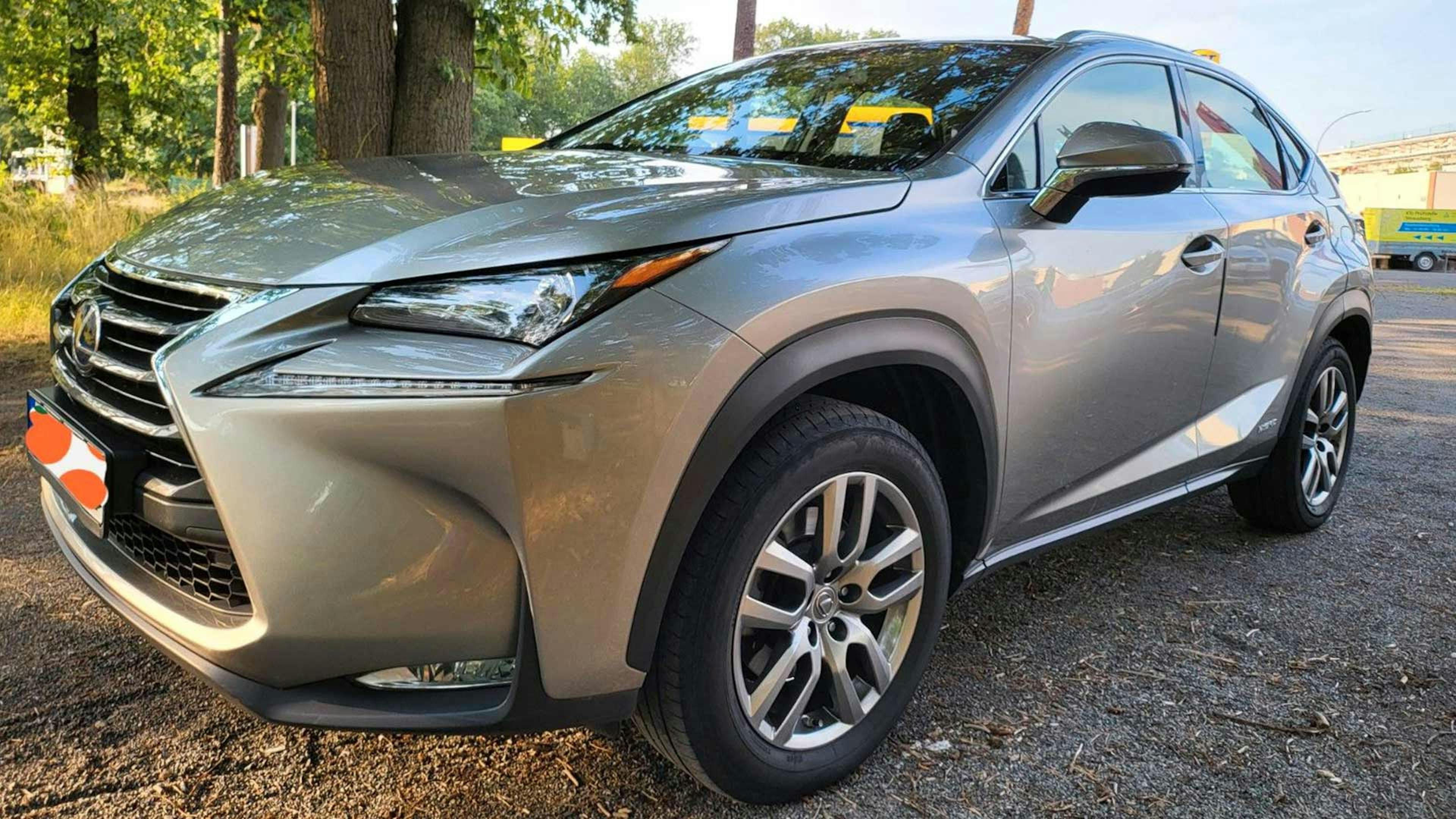 Ein silberner Lexus NX steht auf einem Parkplatz.