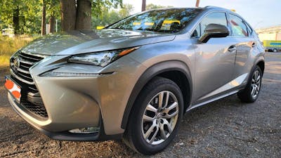 Ein silberner Lexus NX steht auf einem Parkplatz.