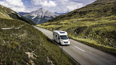Ein Dethleffs Just 90T Wohnmobil fährt eine Landstraße entlang.