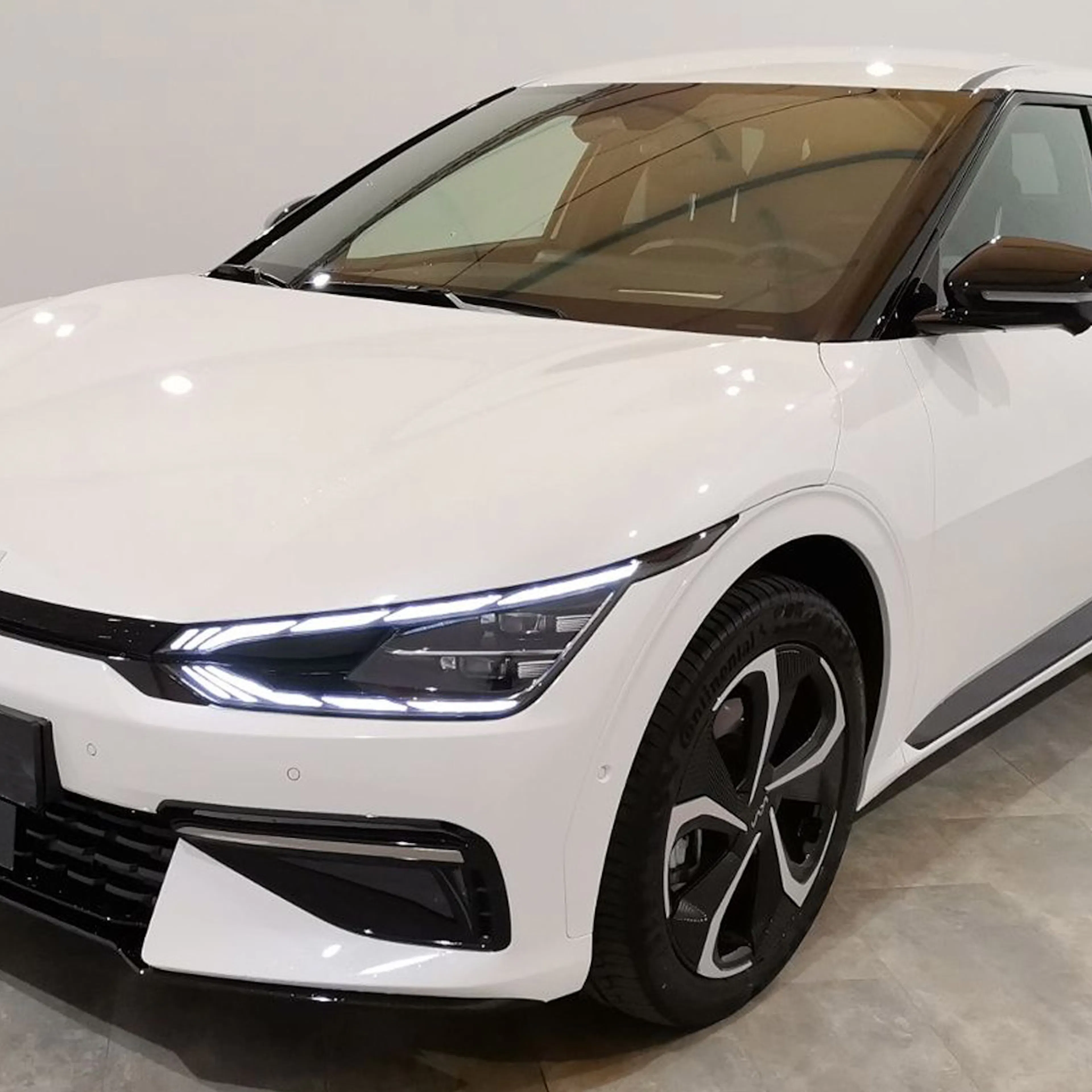 Ein weißer Kia EV6 steht in einem Raum mit hellgrauem Boden und weißen Wänden.