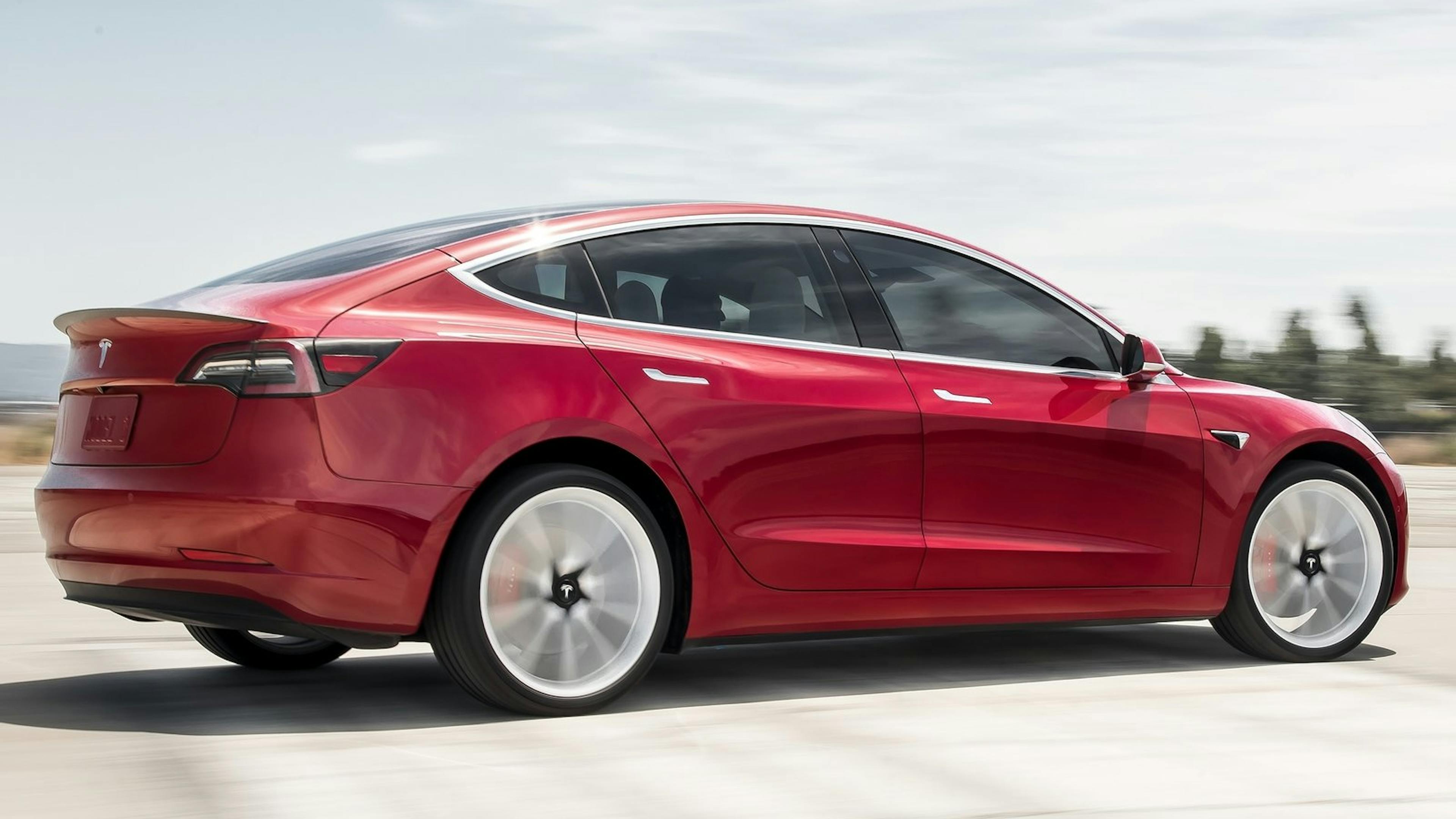 Roter Tesla Model 3 fährt. 