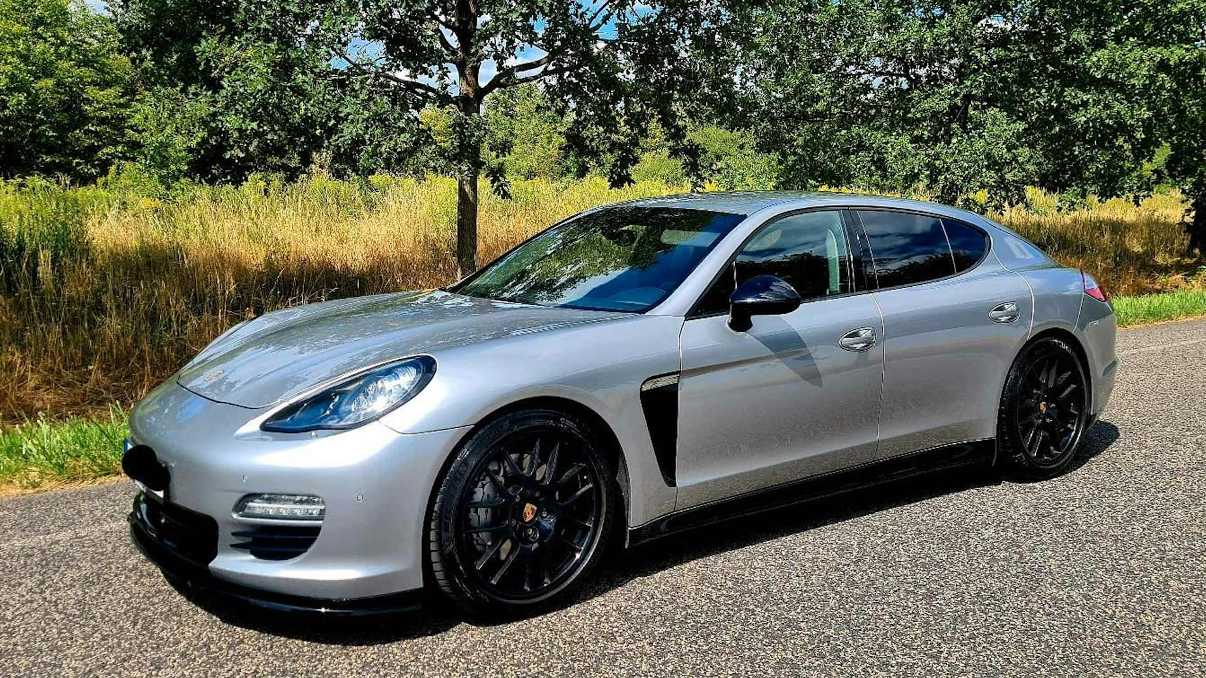 Ein silberner Porsche Panamera der ersten Generation steht am Rand einer Landstraße.