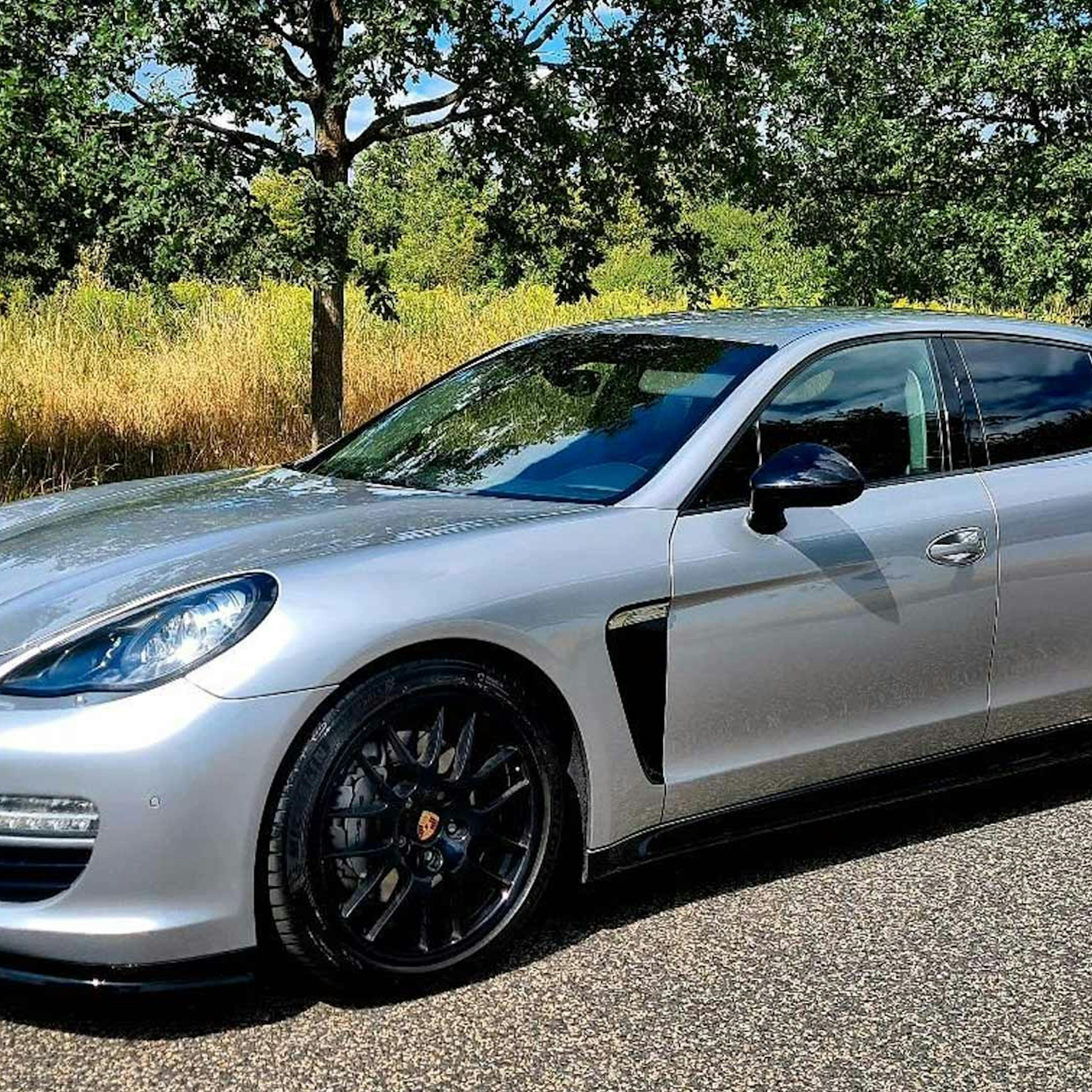 Ein silberner Porsche Panamera der ersten Generation steht am Rand einer Landstraße.