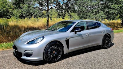 Ein silberner Porsche Panamera der ersten Generation steht am Rand einer Landstraße.
