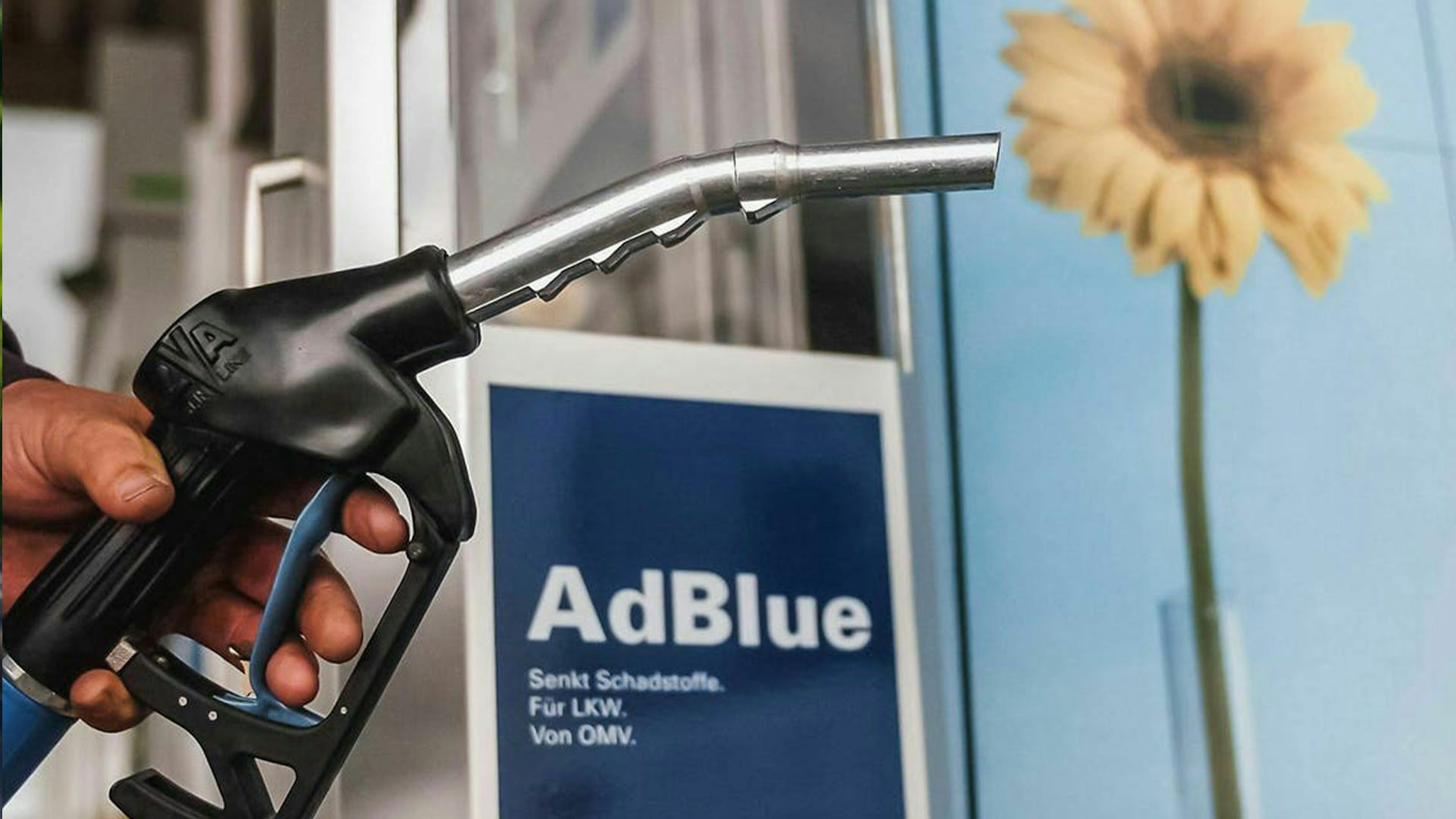 Eine Hand hält den Zapfhahn einer Tanksäule mit AdBlue-Dieseltreibstoff.