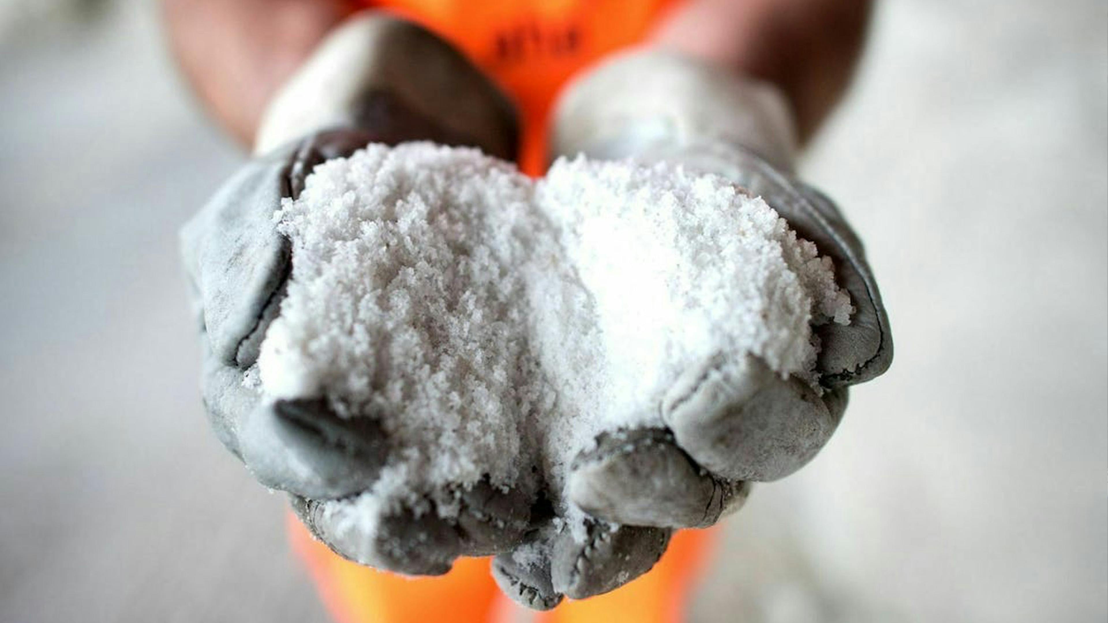 Eine Person hält Streusalz in den Händen.