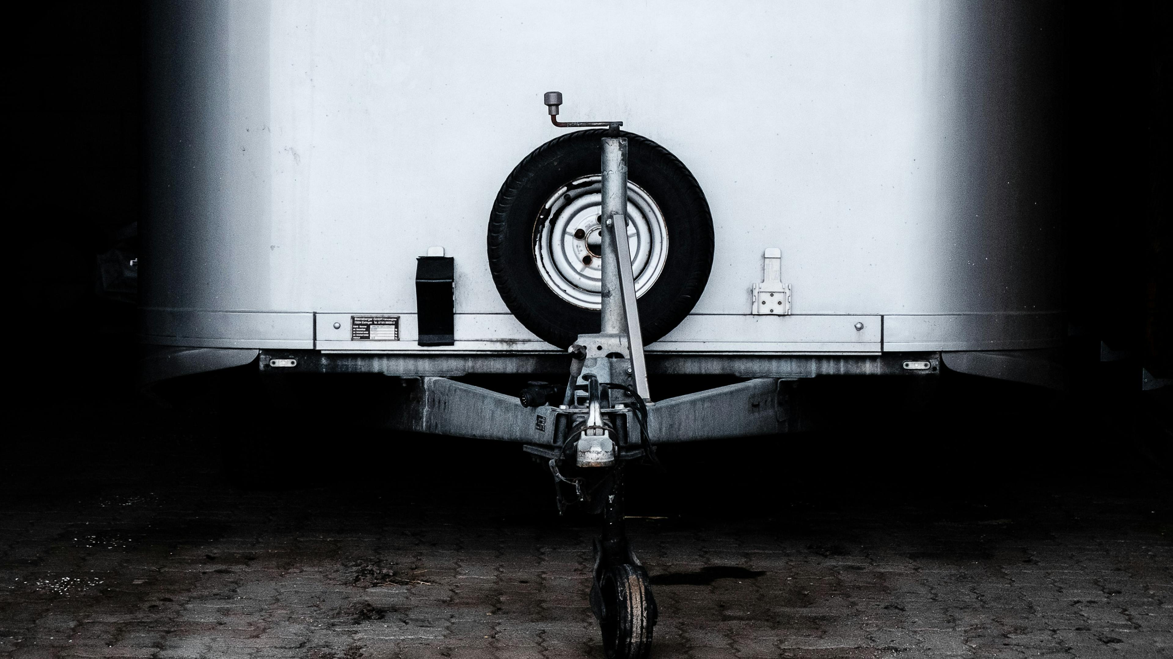 Detail eines weißen Pkw-Anhängers mit schwarzem Ersatzrad